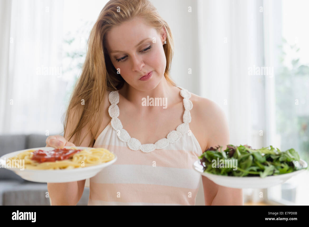 Woman choosing between pasta and salad Stock Photo