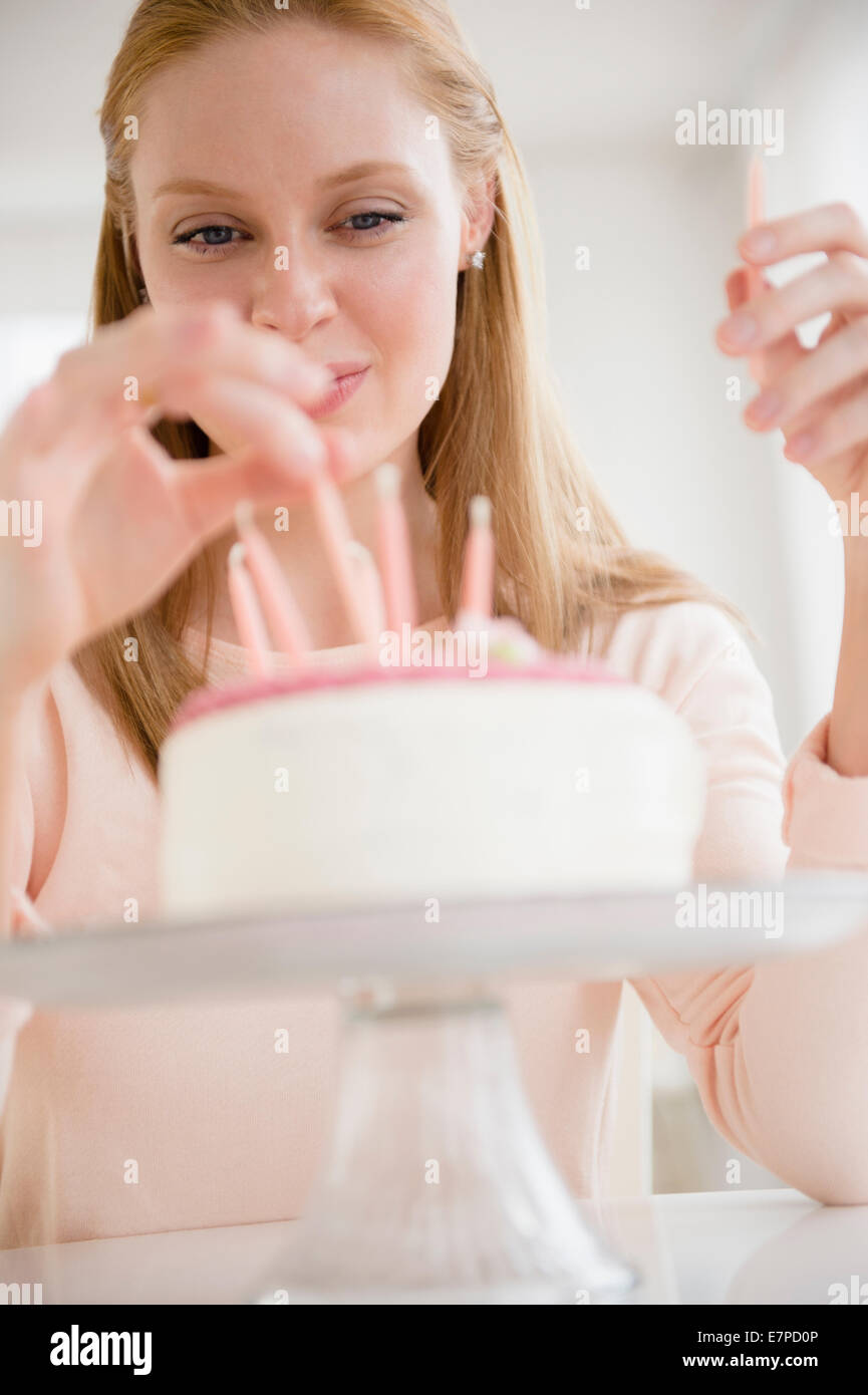 Woman putting candles on birthday cake Stock Photo