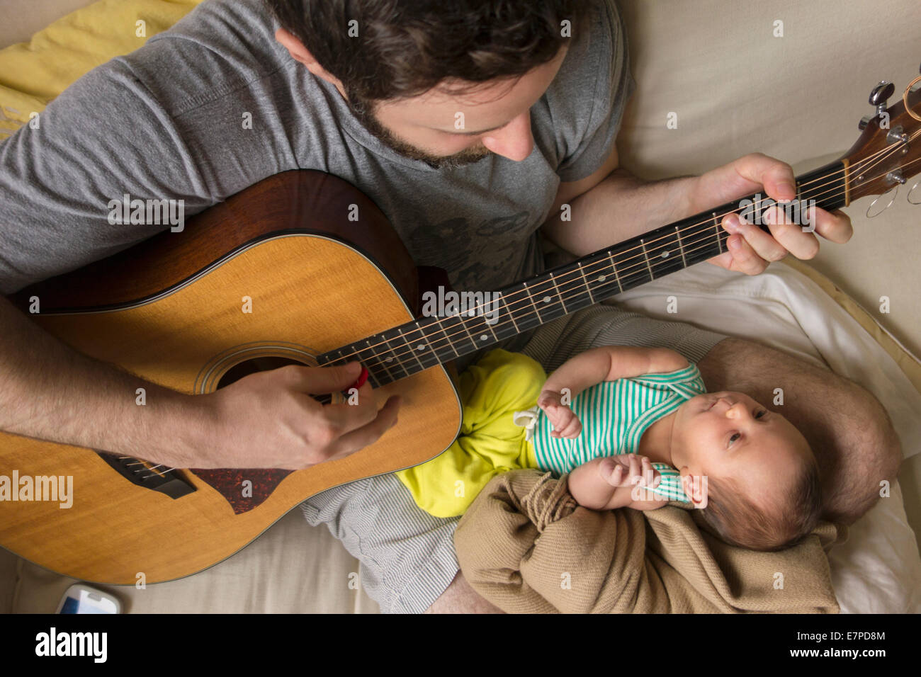 Father playing guitar for newborn daughter Stock Photo