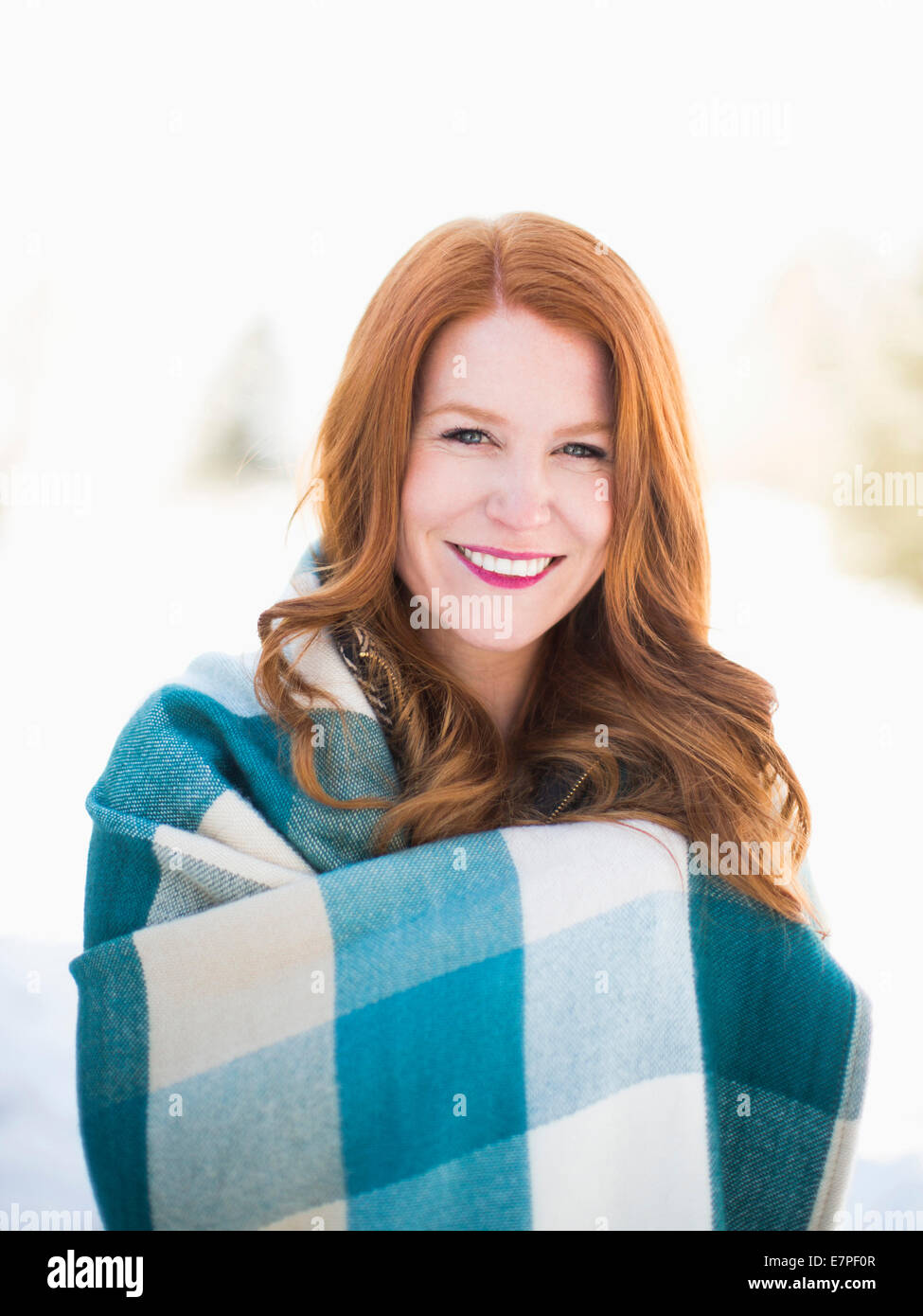 Portrait of mid adult woman wrapped in checked blanket Stock Photo