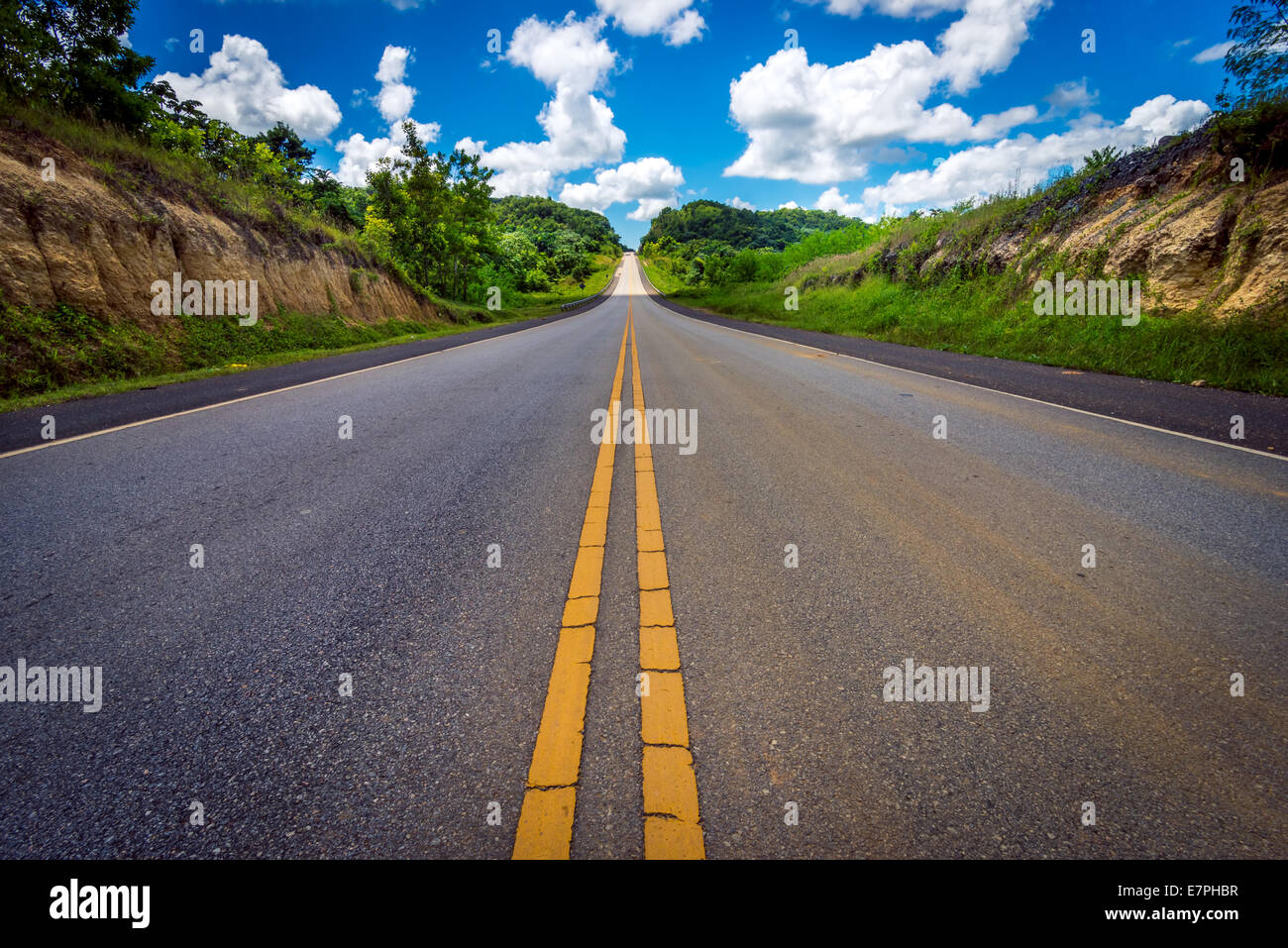 asphalt road through the field and clouds on blue sky, on summer day ...