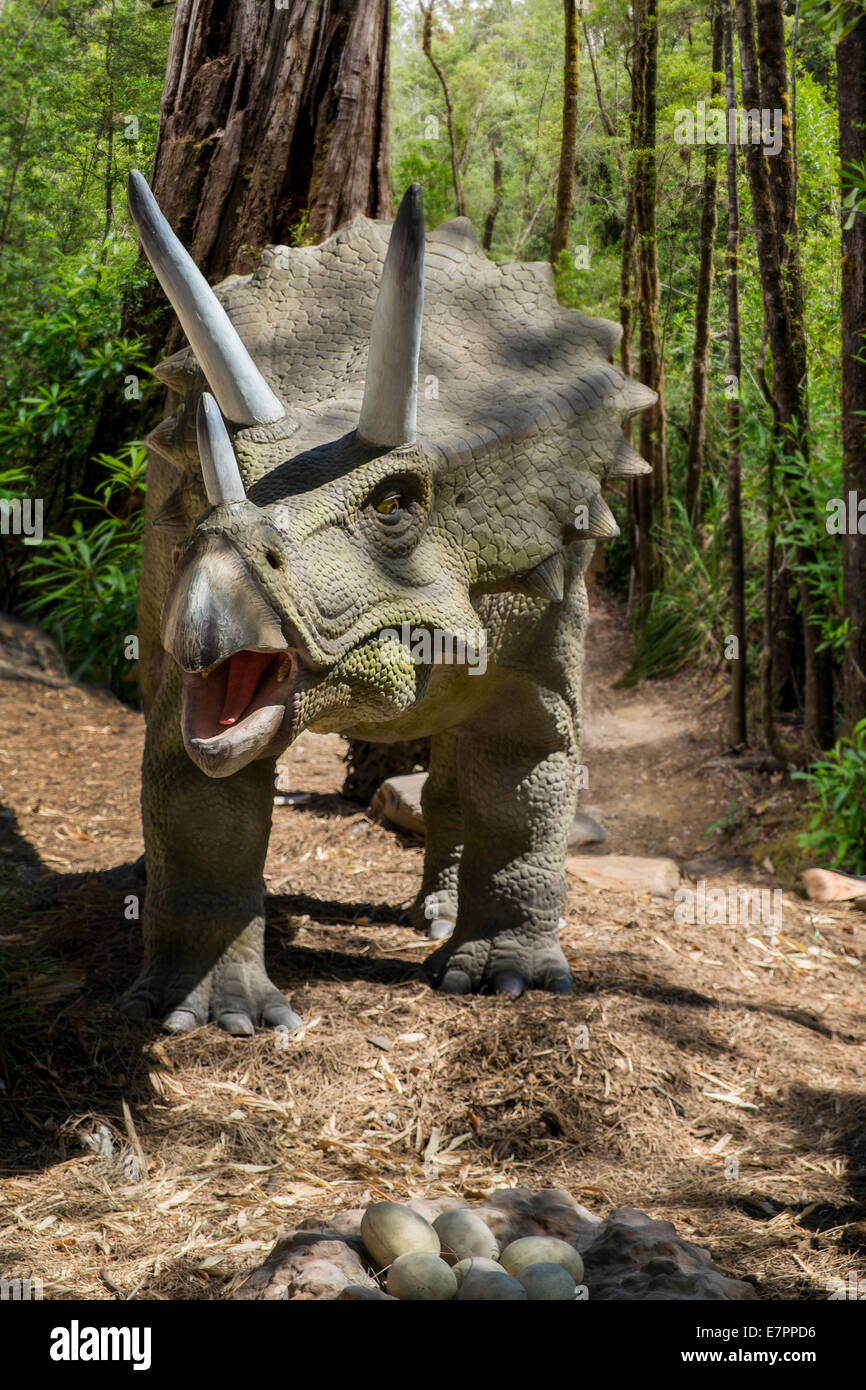 Life size Triceratops dinosaur figures prowl the forest Stock Photo