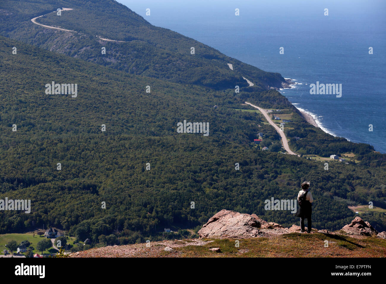 Woman standing on Roberts Mountain overlooking Pleasant Bay and the Cabot Trail, Cape Breton Island, Nova Scotia, Canada Stock Photo