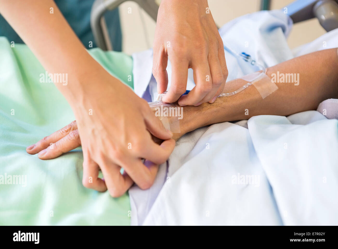 Female Nurse Attaching IV Drip On Male Patient's Hand Stock Photo