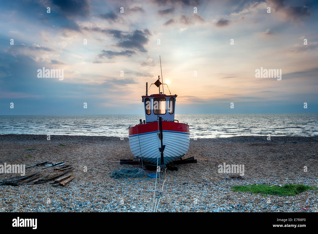 Red and white wooden fishing boat on a shingle beach Stock Photo - Alamy