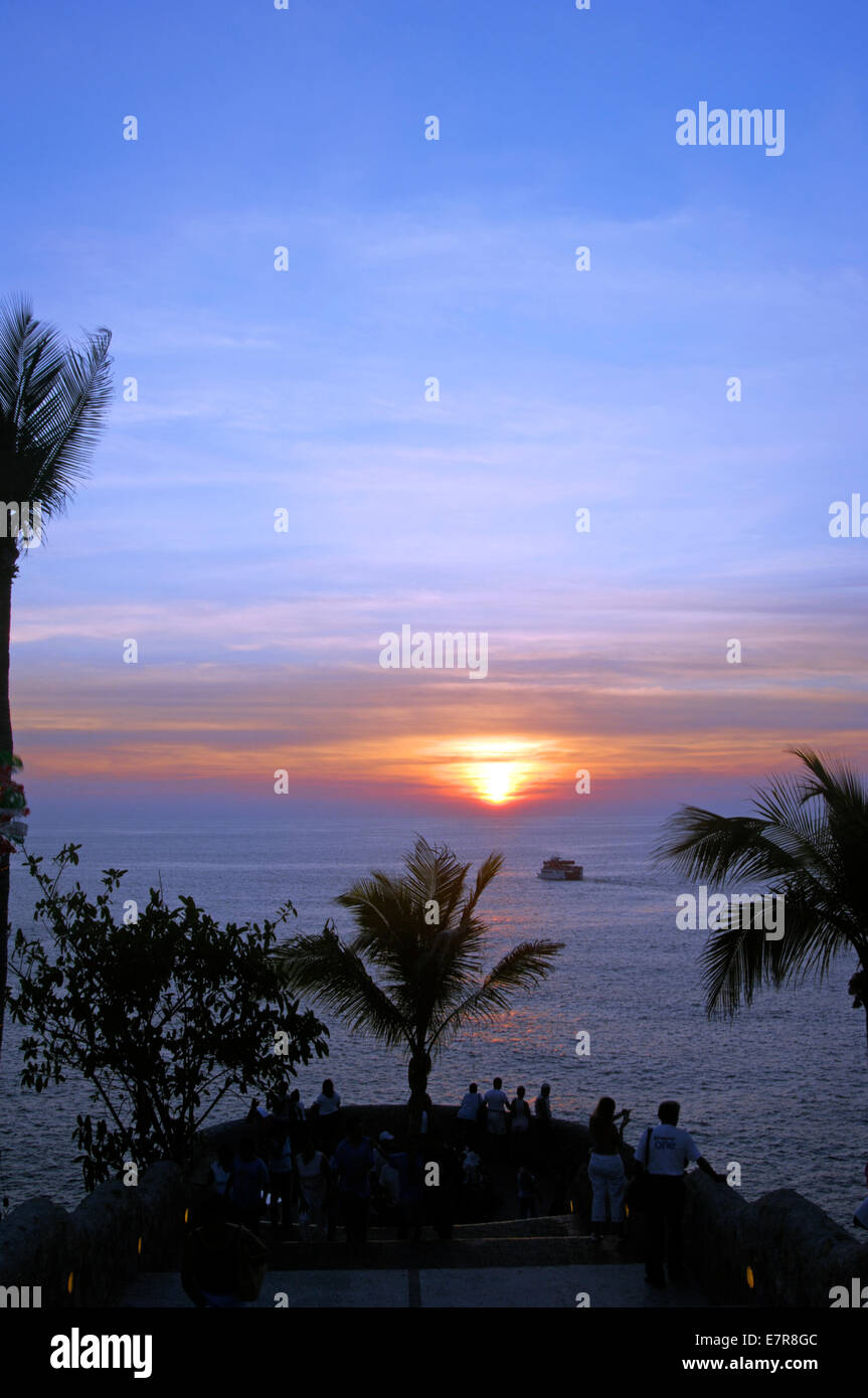 A small boat sails off into the sunset in Acapulco Stock Photo