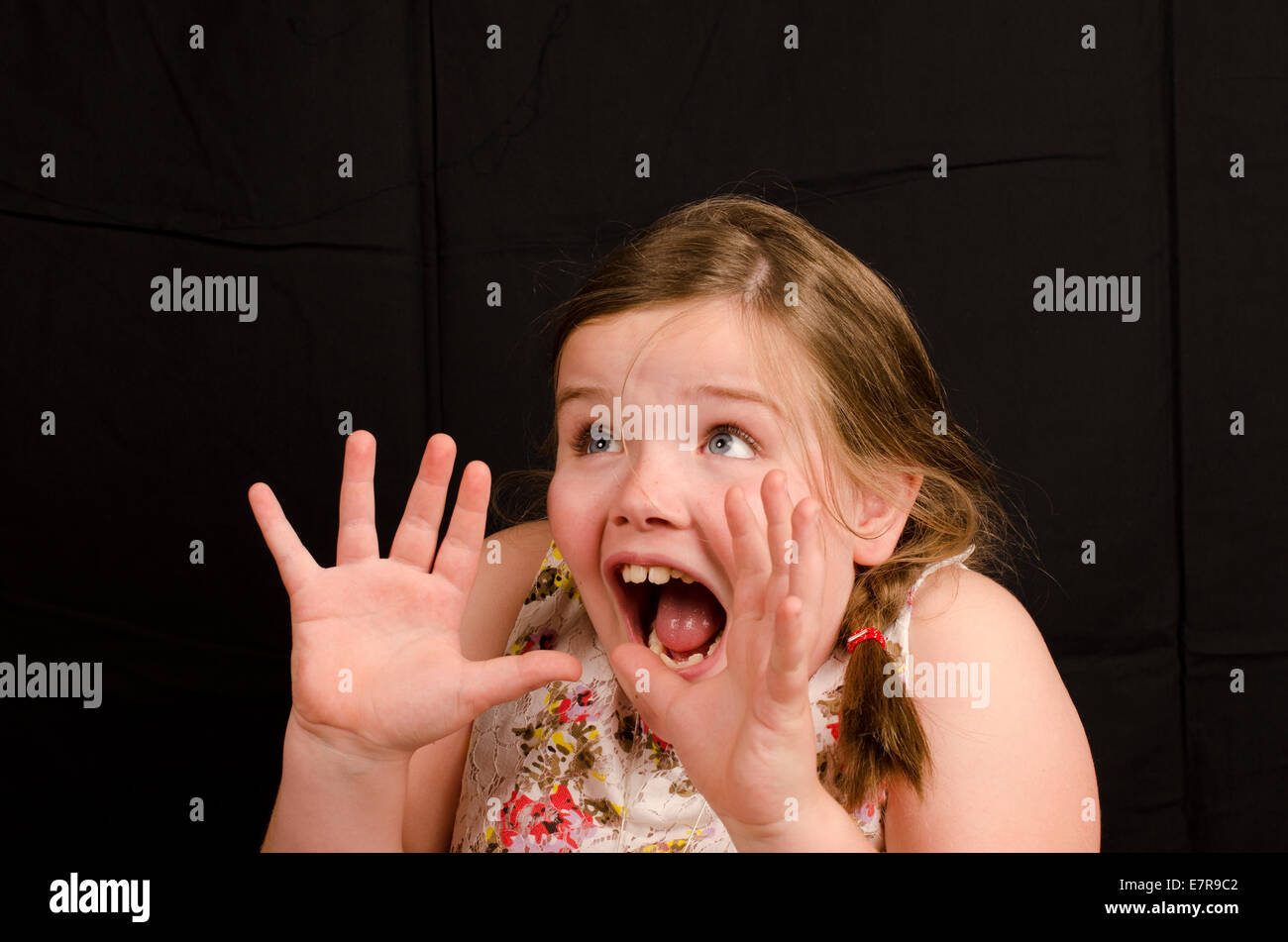 Image of an 8 year old girl on a black background with a  surprised expression Stock Photo