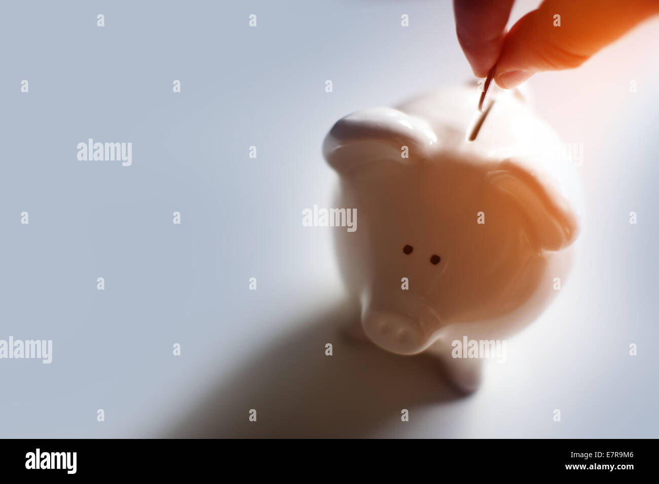 Male hand putting a coin into piggy bank Stock Photo - Alamy