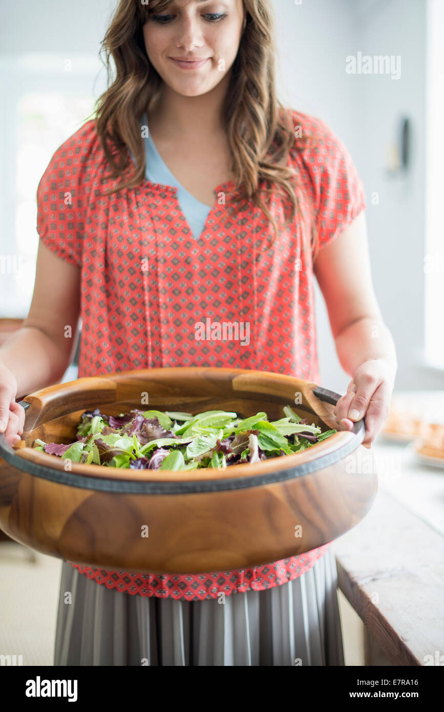 A woman carrying food to a table, preparing for a family meal. Stock Photo