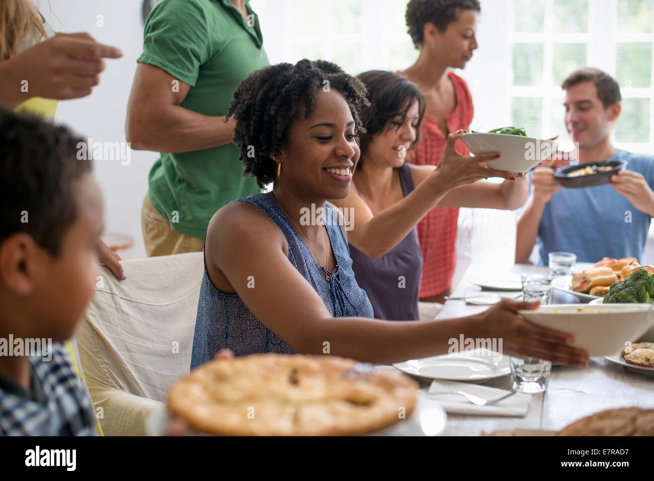 A family gathering, men, women and children around a dining table sharing a meal. Stock Photo