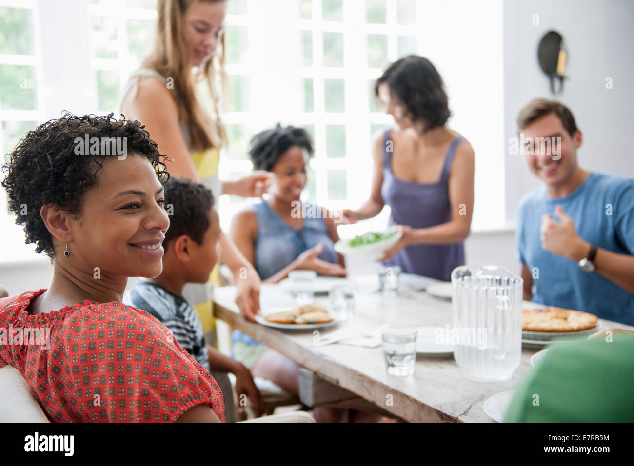 A family gathering for a meal. Adults and children around a table. Stock Photo