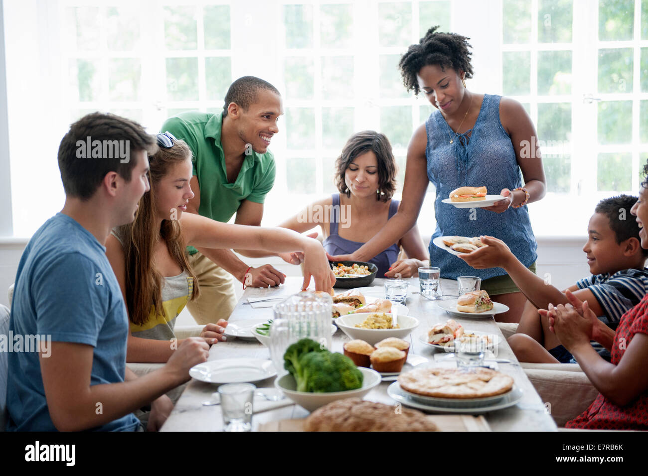 A family gathering for a meal. Adults and children around a table. Stock Photo