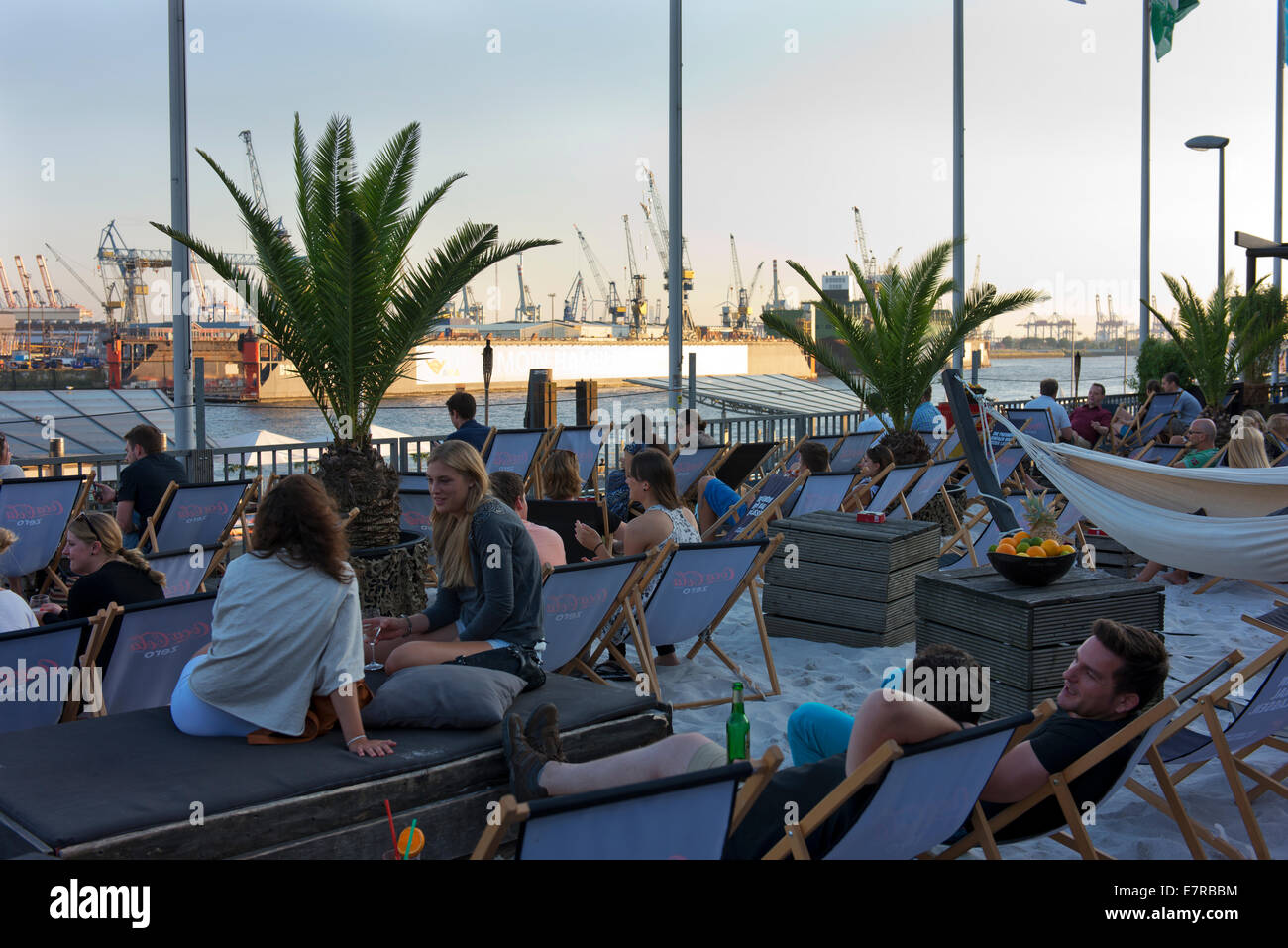 Young people relax with a drink at a beach bar on the Spree River at Landungsbrucke. Stock Photo