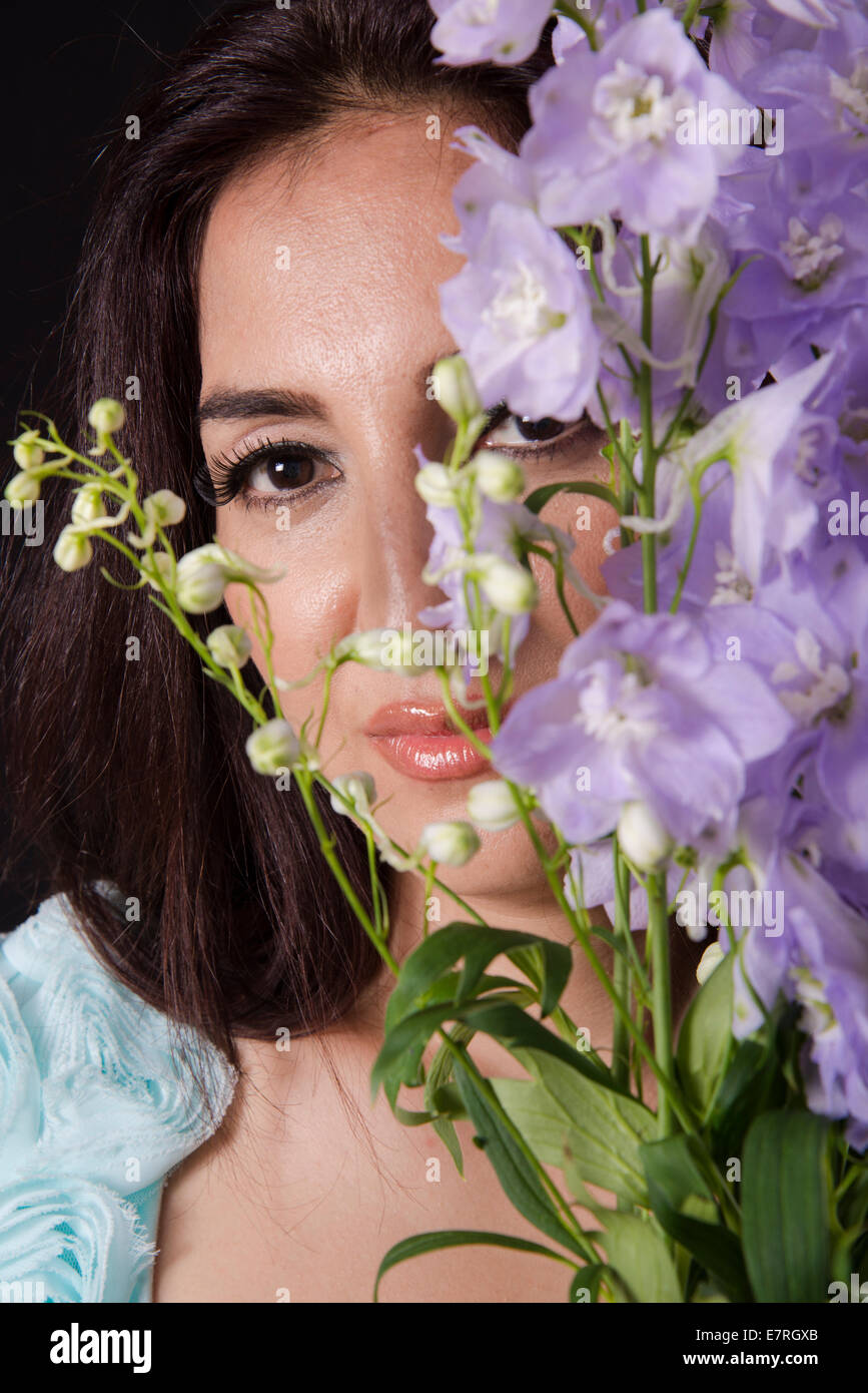 Romantic looking woman holding flowers in front of her face Stock Photo