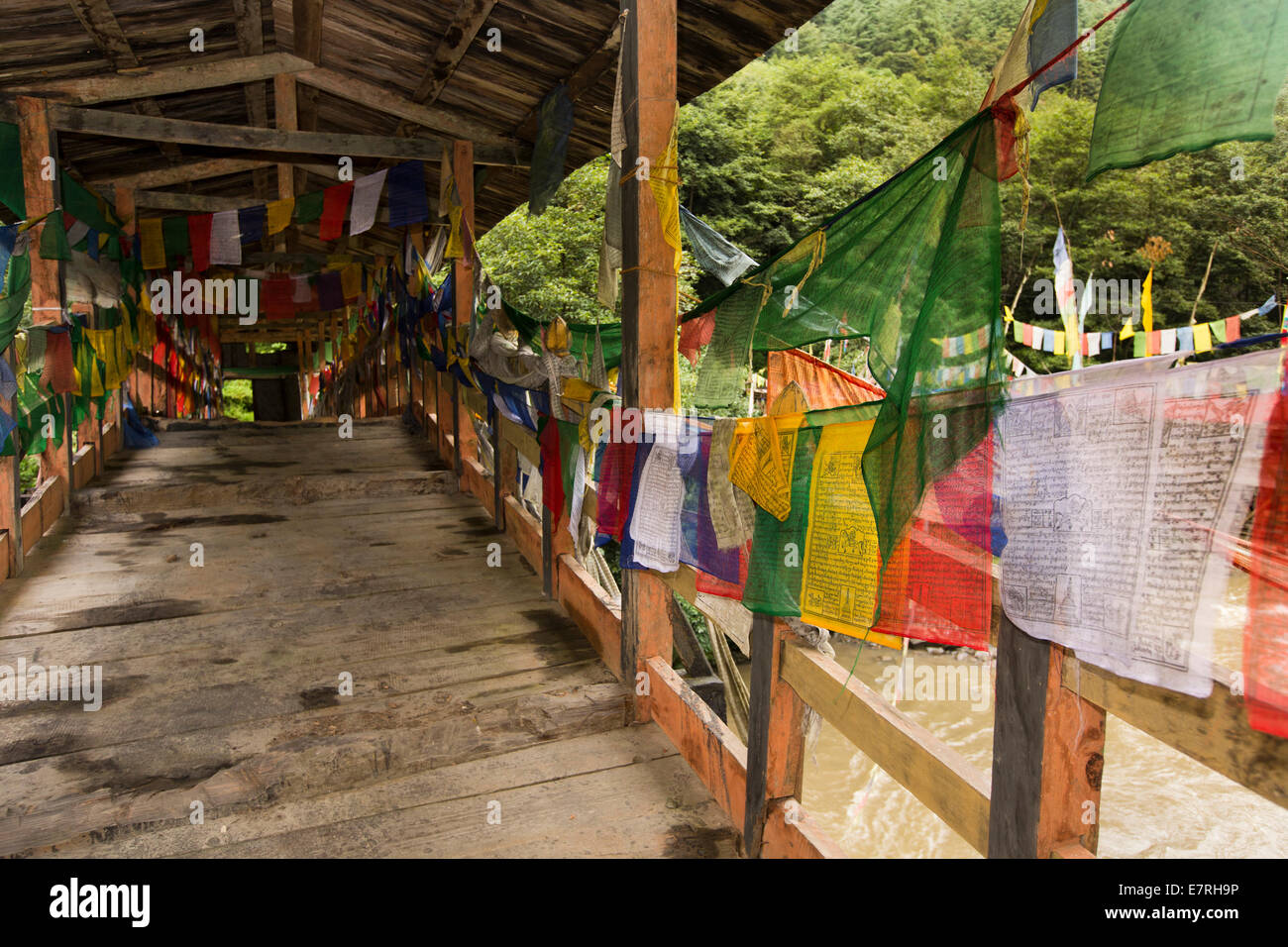Eastern Bhutan, Trashi Yangtse, prayer flags lining old wooden bridge over Dongdi Chu river Stock Photo