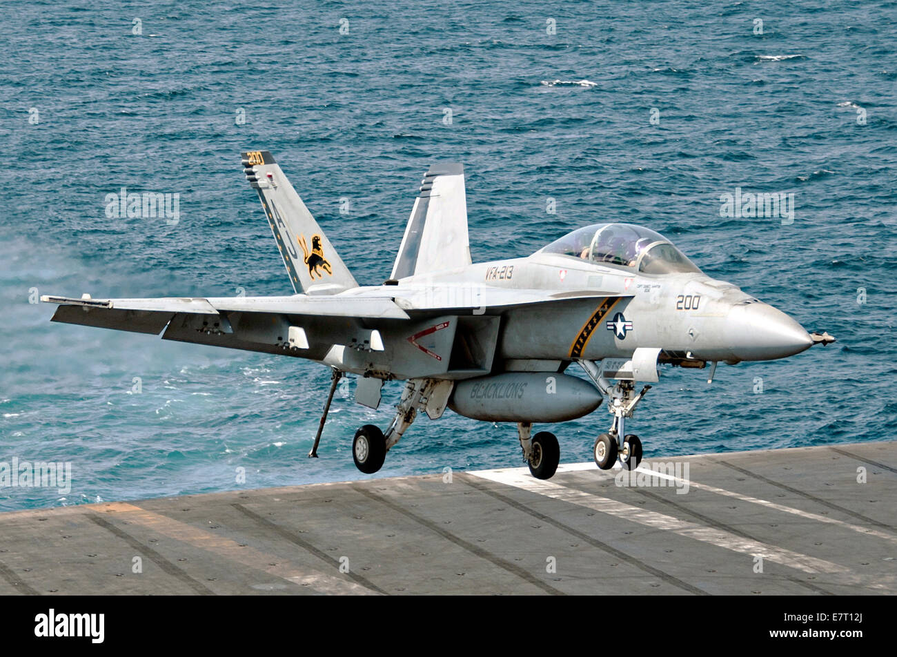 A US Navy F/A-18F Hornet fighter aircraft lands on the flight deck of the aircraft carrier USS George H.W. Bush after retiring from a combat sortie against ISIS targets September 23, 2014 in the Persian Gulf. The military launched the first direct strikes on ISIS targets inside Syria. Stock Photo