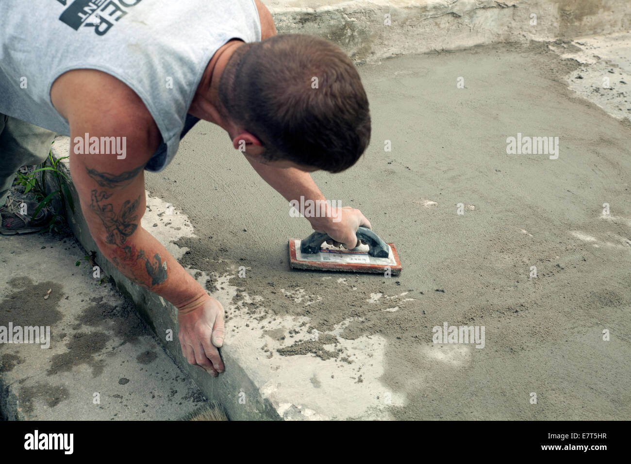 Workman smooths  a skim coating of cement on old stairway. Stock Photo