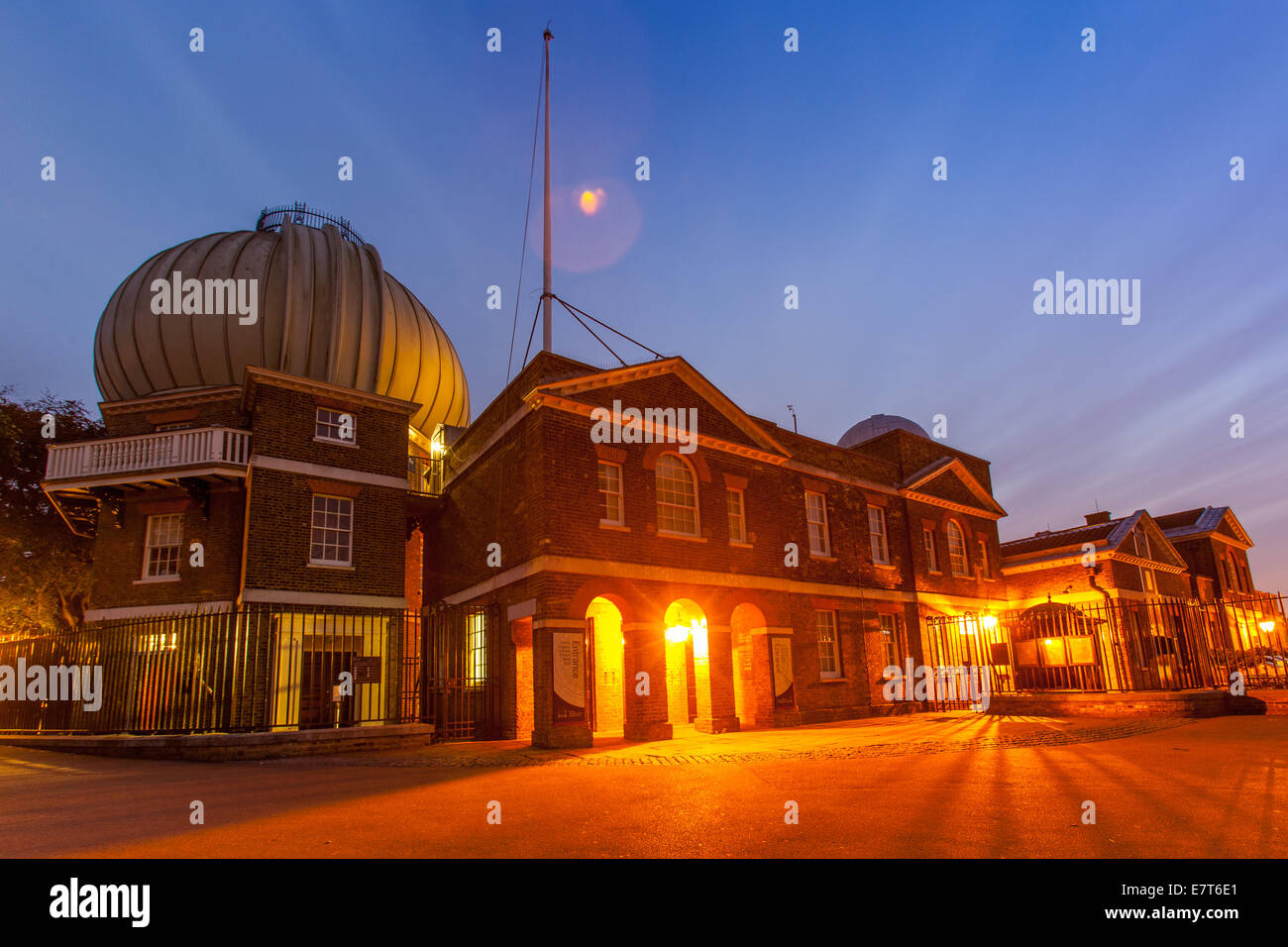 Greenwich Royal  Observatory  in the evening light. Orange lights inside contrast with the blue night sky. Landscape format Stock Photo