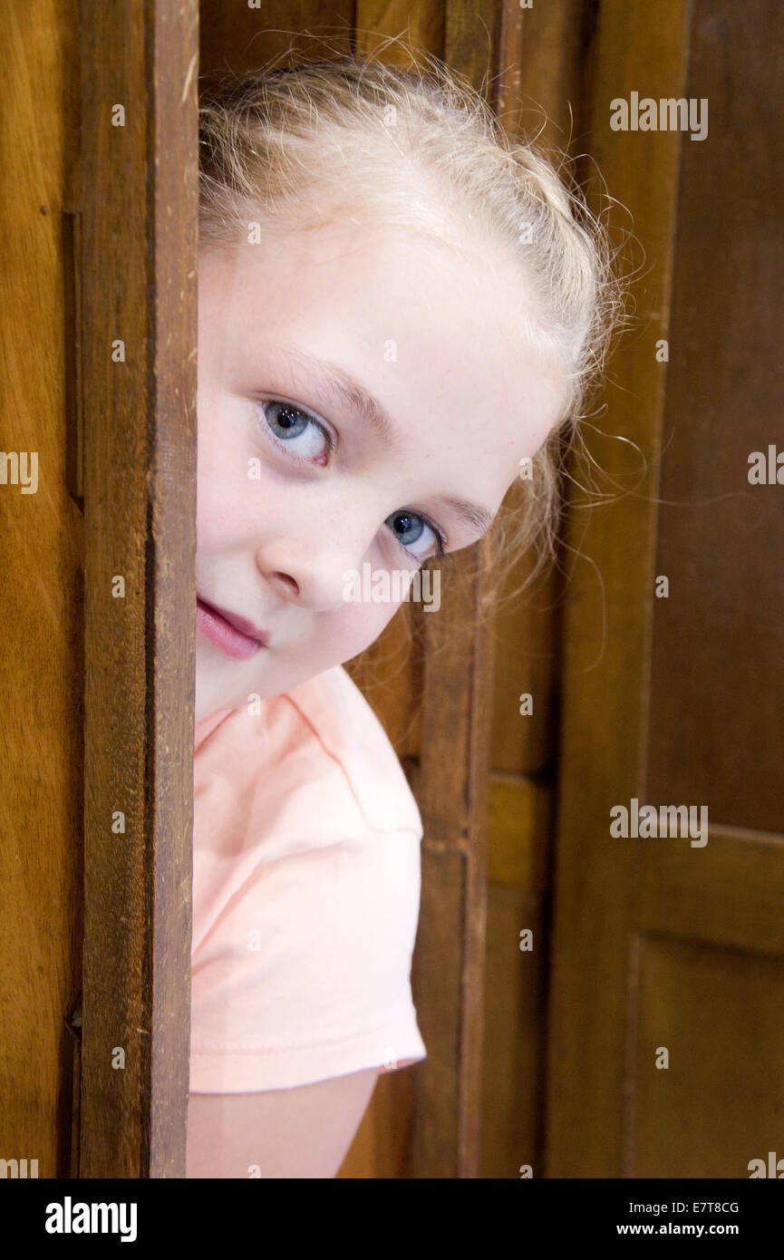 Young girl hiding behind a door Stock Photo Alamy