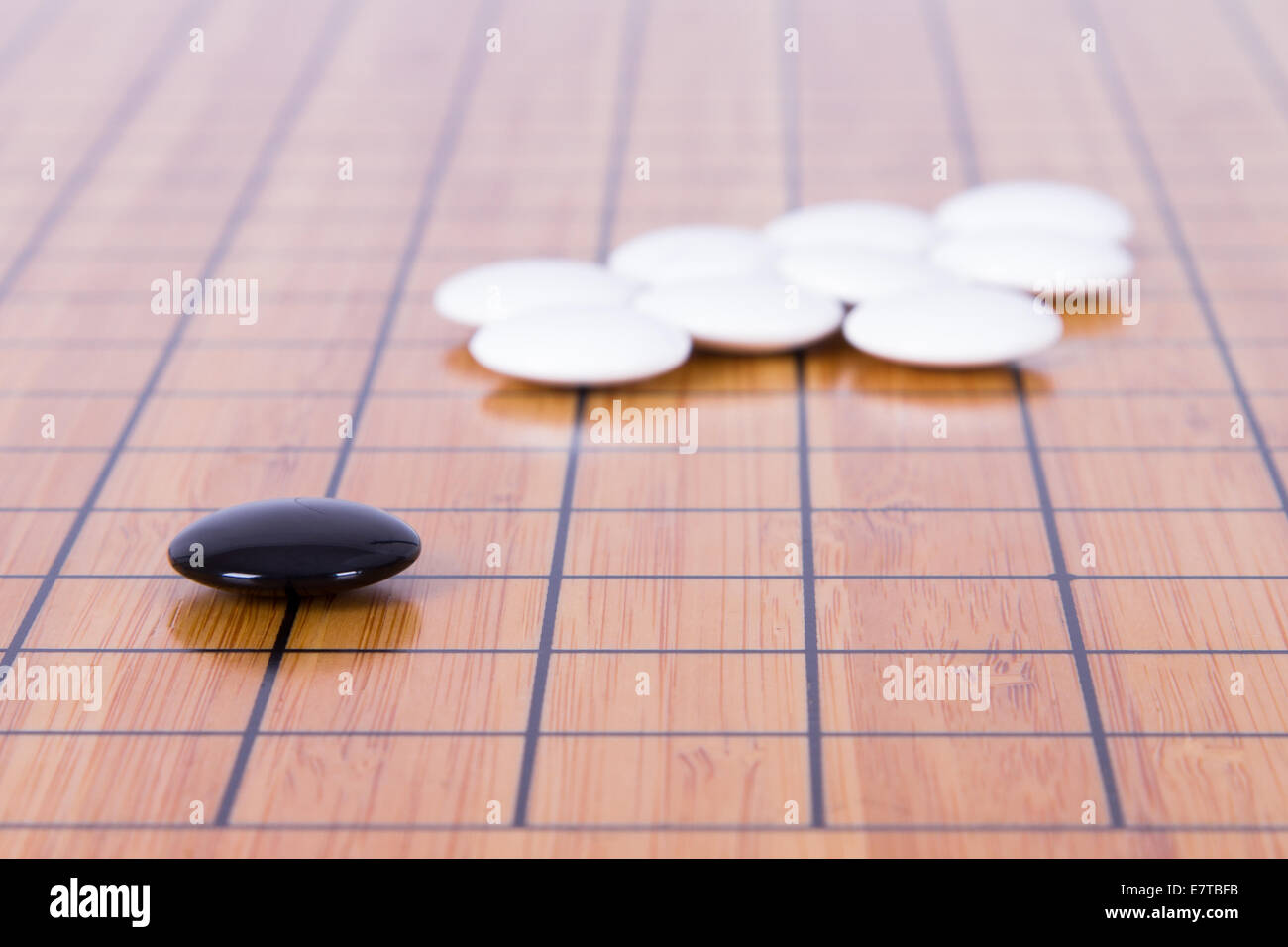 Black stone standing out from white pieces on Chinese go game board ...