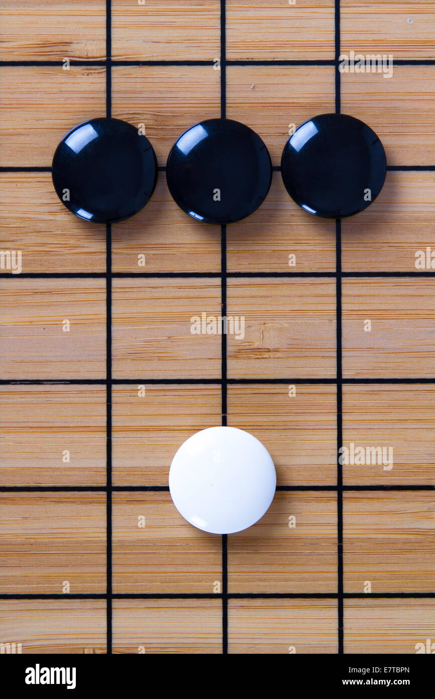 White stone standing out from black pieces on Chinese go game board ...