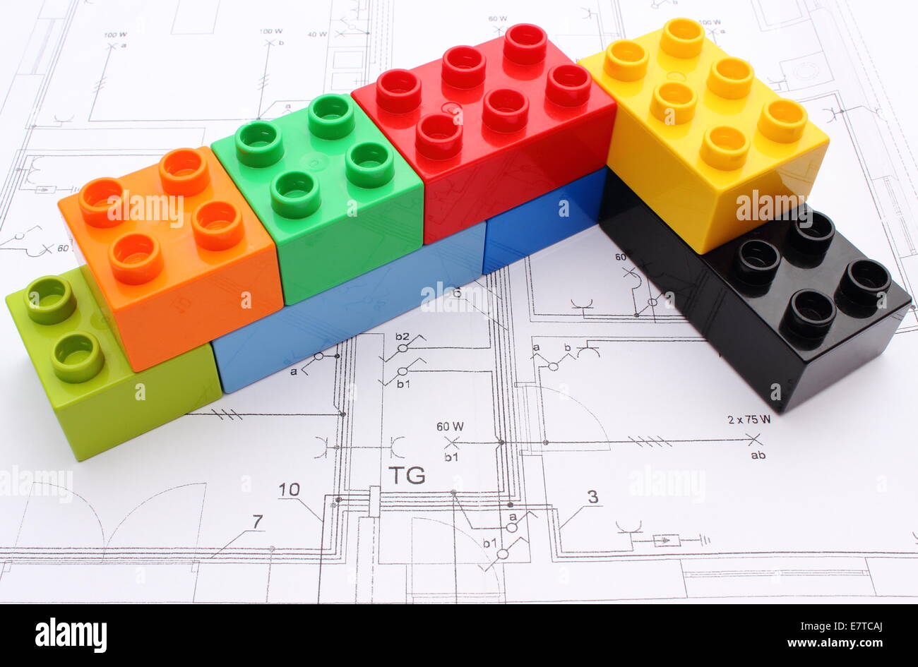 Wall of colorful building blocks lying on construction drawing of house