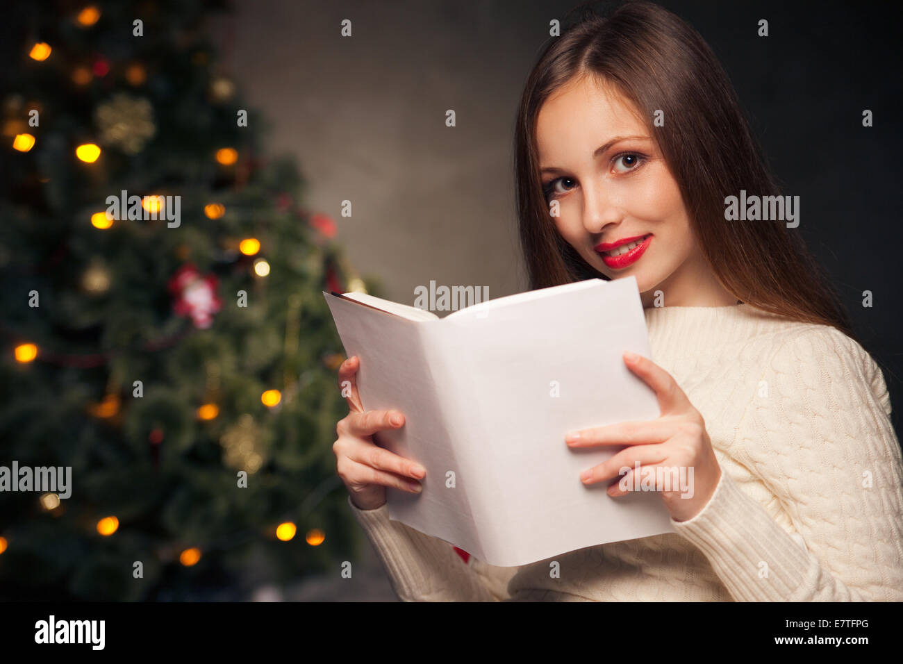 Woman in front of Christmas tree reading book Stock Photo Alamy