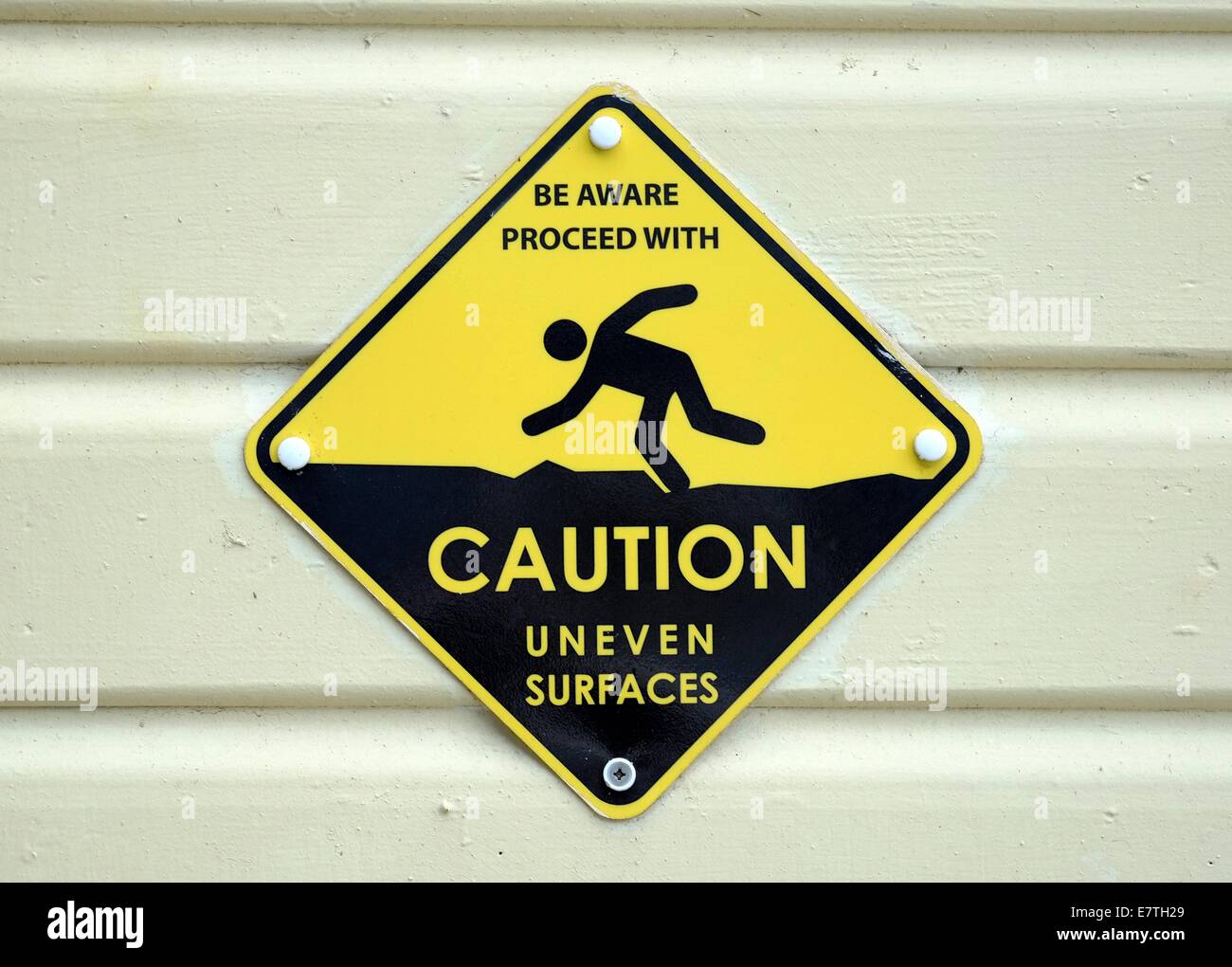 Be aware proceed with caution uneven surfaces warning sign england uk Stock Photo
