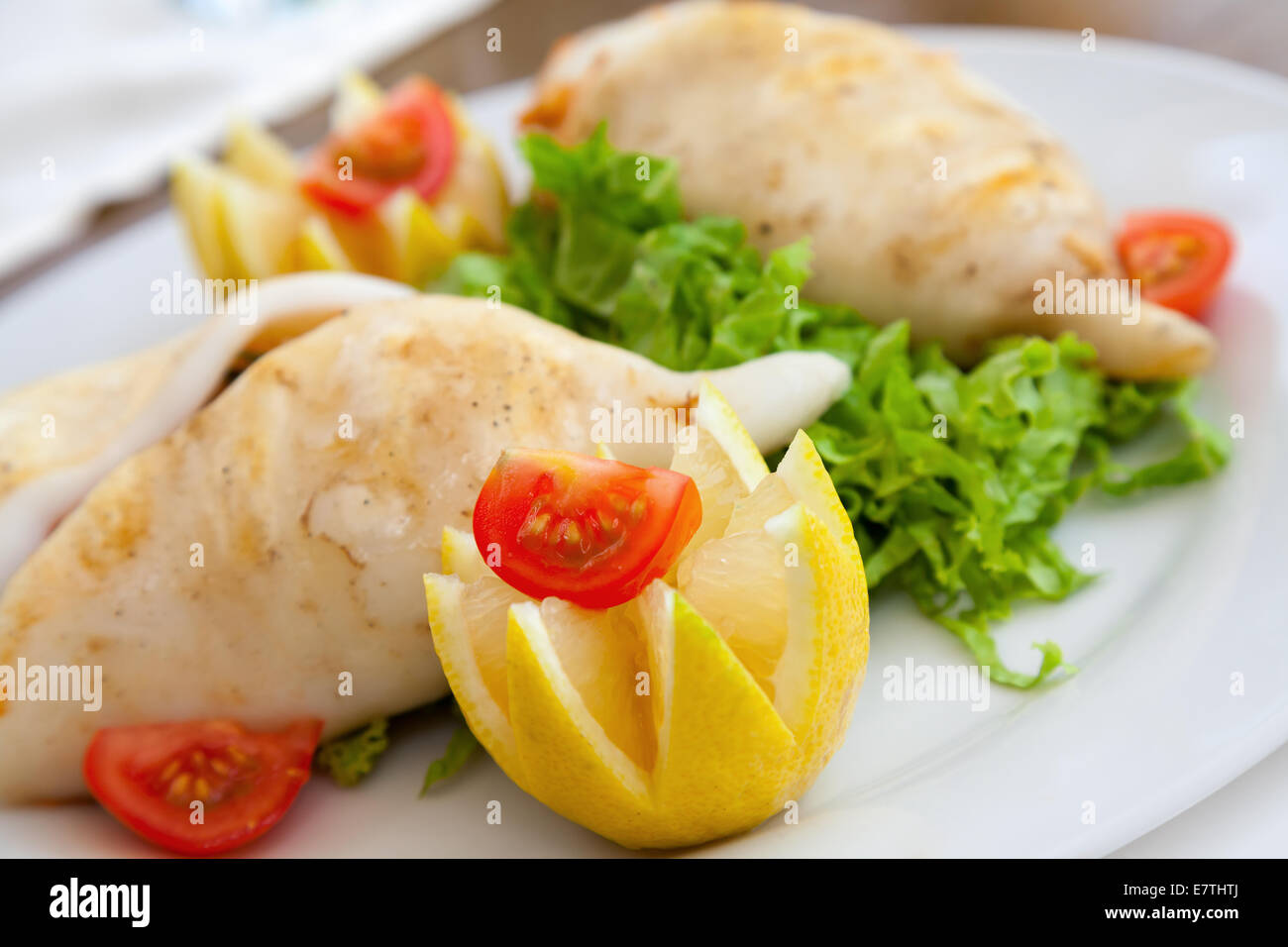 Squid stuffed with seafood on white plate in restaurant Stock Photo