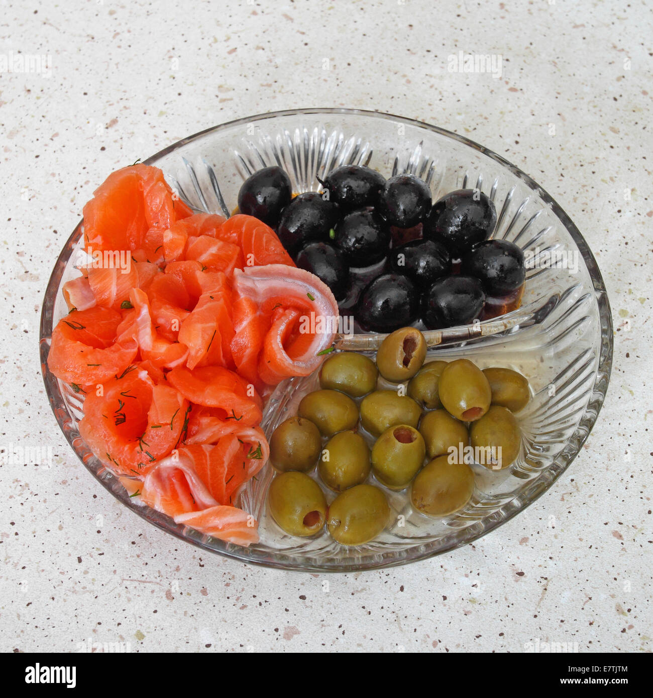 Plate with black and green olives and slices of red salmon Stock Photo