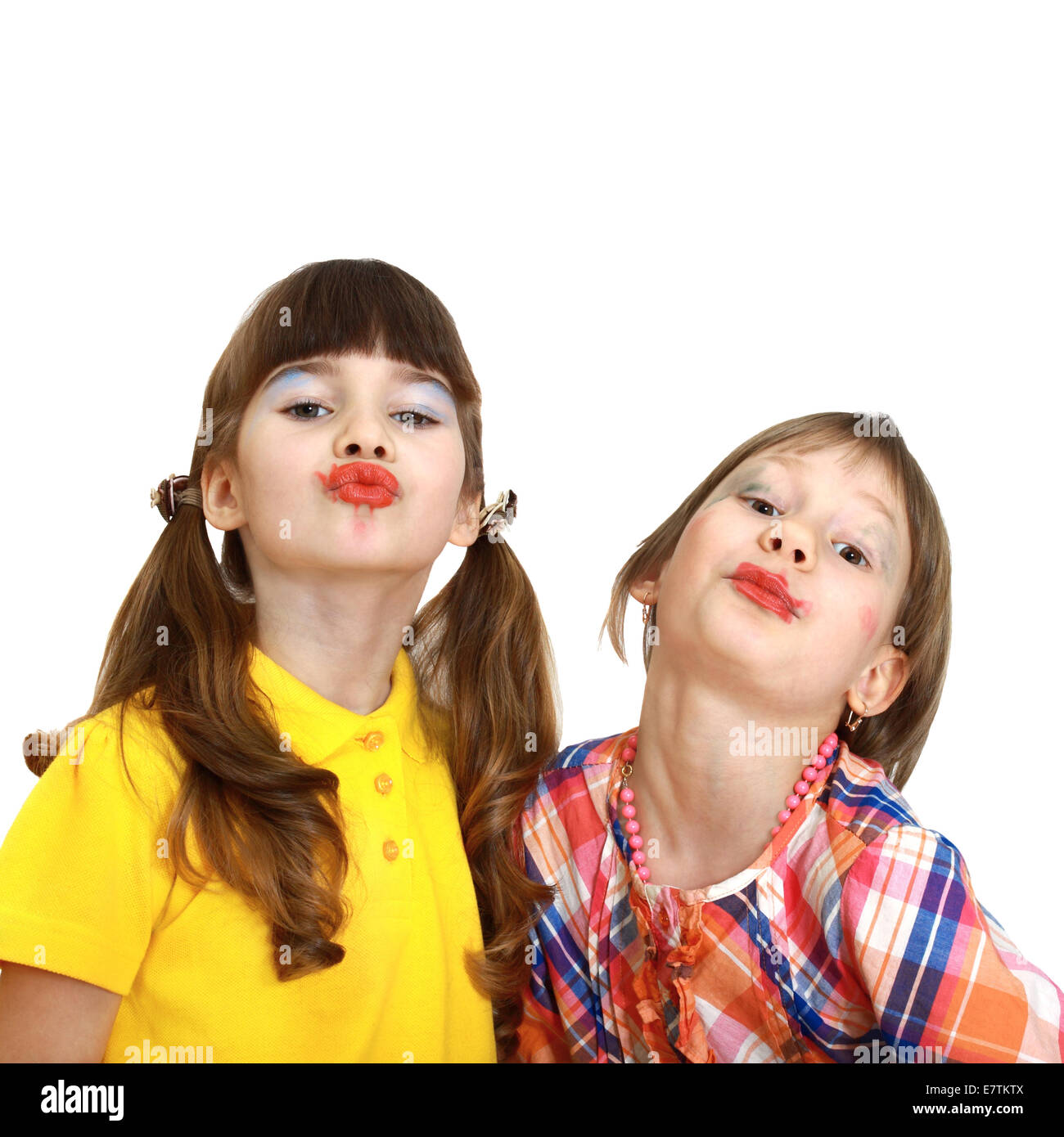 Two cute girls with crooked wrong makeup demonstrate painted lips isolated on white background Stock Photo