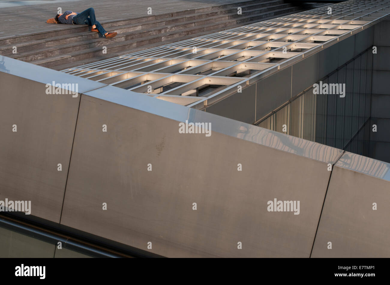 Young man sleeping on the steps of a modern building Stock Photo