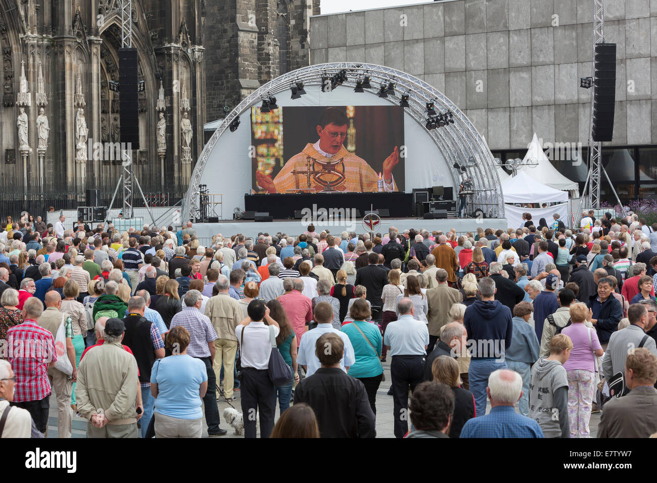 A crowd of people observes the inauguration of Rainer Maria Kardinal Woelki on a big screen in front of the cathedral Stock Photo
