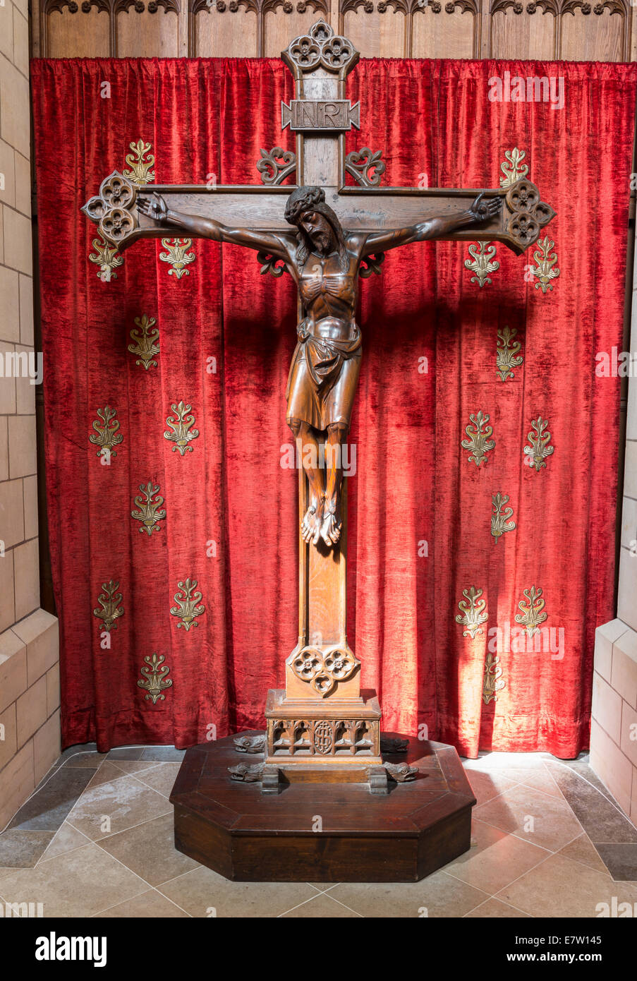 The interior of Buckfast Abbey showing a large cross of Jesus against a red velvet background. Stock Photo