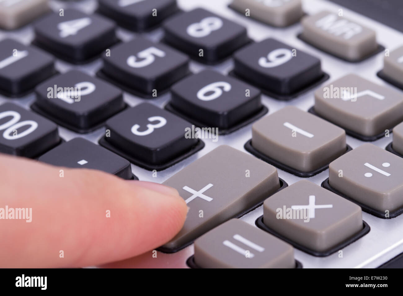 Finger pressing plus button of calculator. Stock Photo
