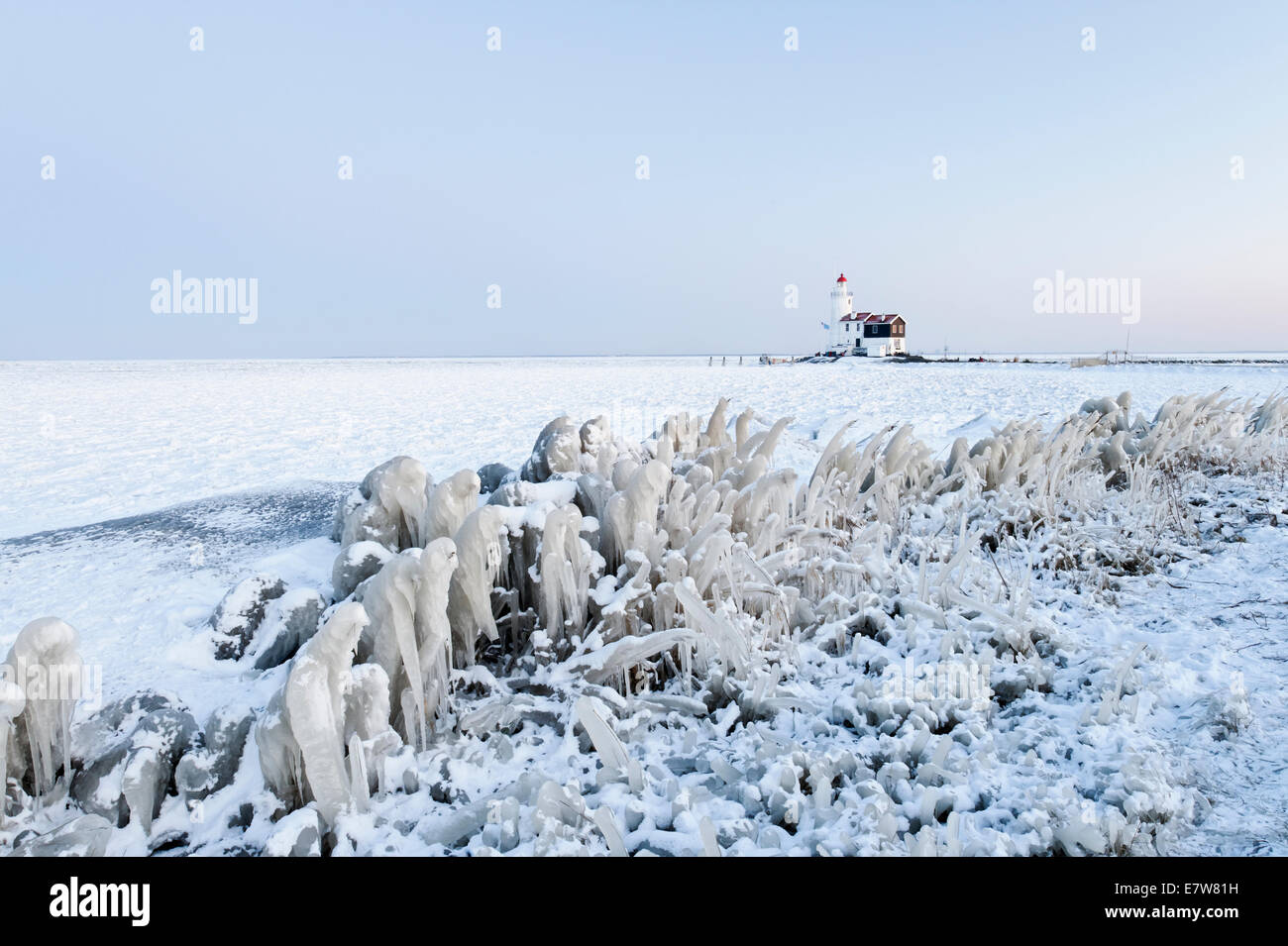 A frozen lake, reeds, and lighthouse in Holland Stock Photo