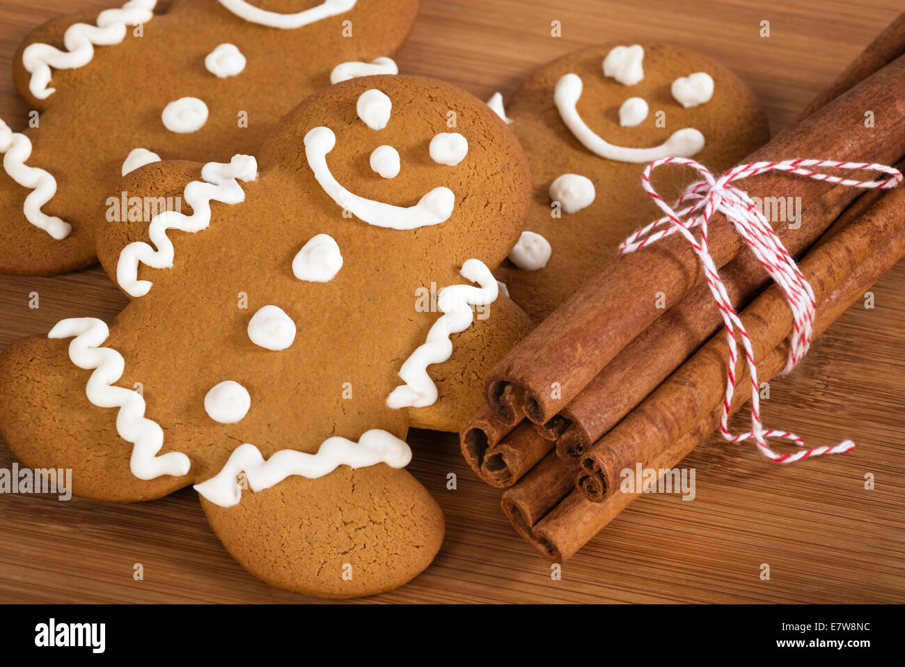Freshly baked gingerbread man cookies with cinnamon sticks on wooden cutting board Stock Photo
