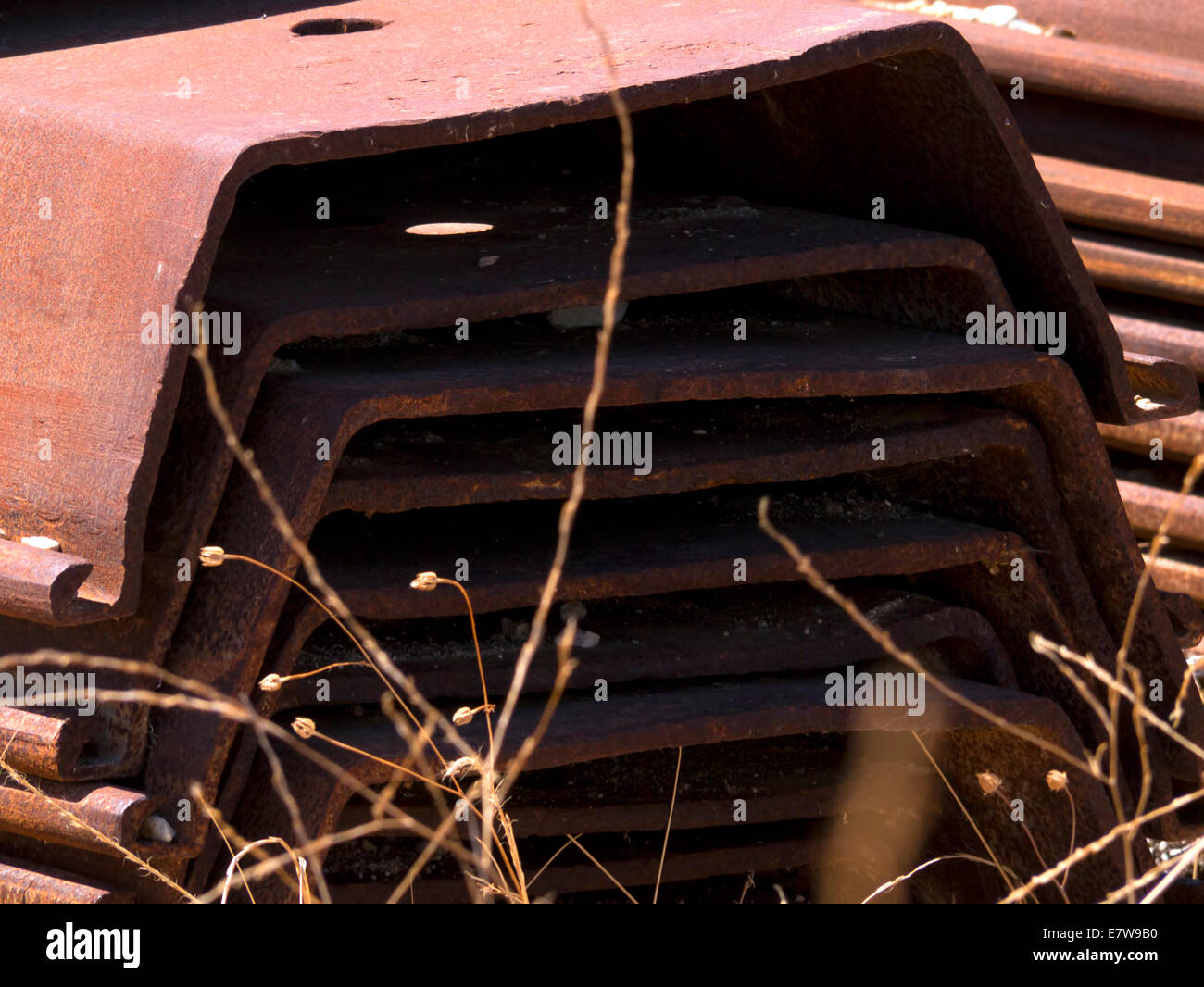 Rusty steel girders stacked up in an empty field in Greece Stock Photo
