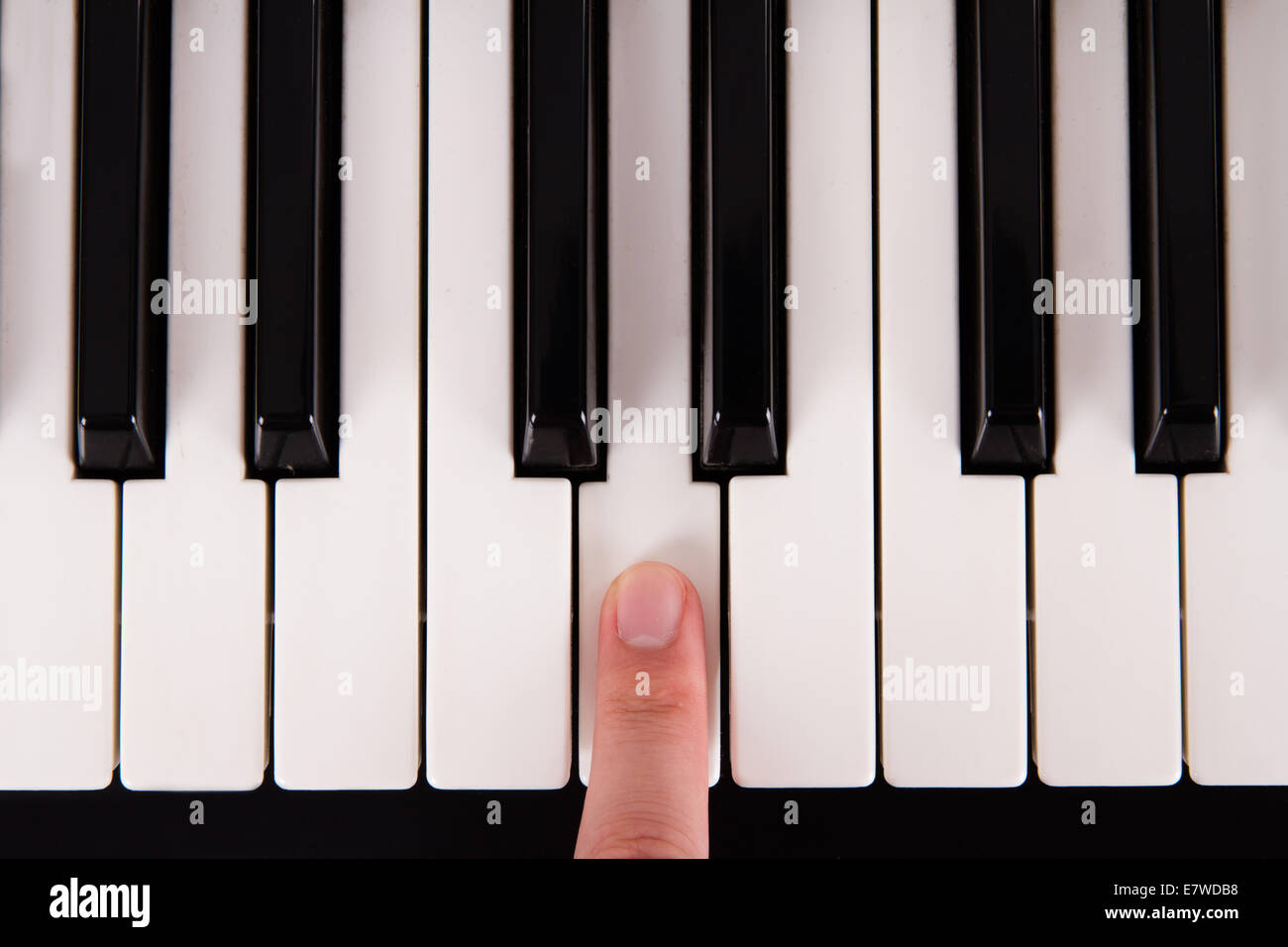 Black and white piano keys and index finder pressing a key Stock Photo -  Alamy