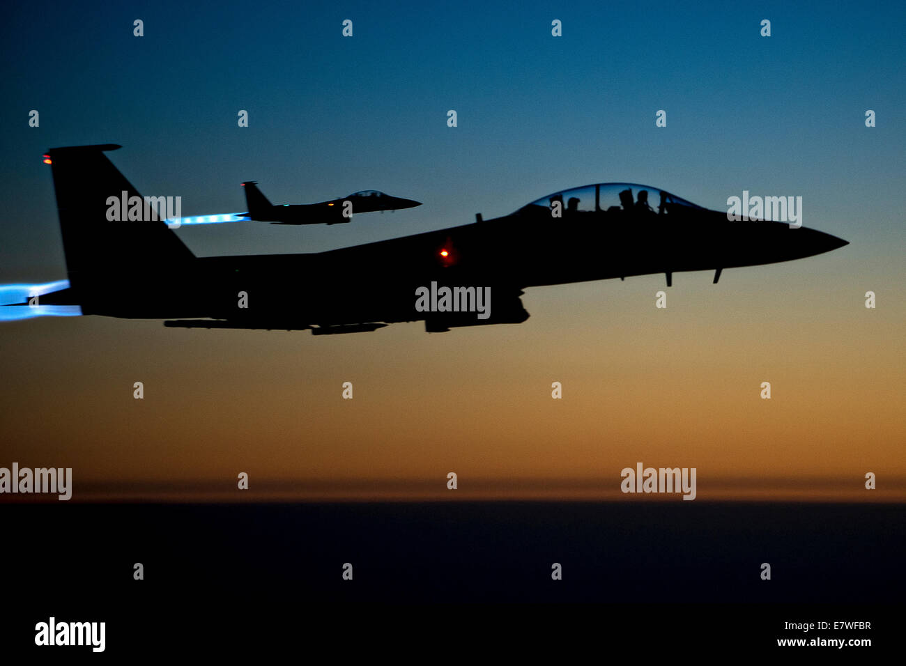US Air Force F-15E Strike Eagle fighter aircraft are silhouetted by the setting sun as they fly over Iraqi airspace after completing combat sorties against ISIS targets in Syria September 23, 2014. The completed their first combat missions over Syria striking at ISIS targets. Stock Photo