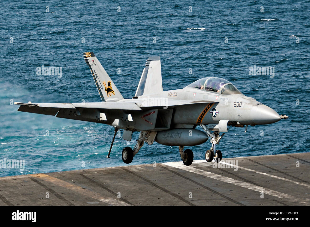 A US Navy F/A-18F Hornet fighter aircraft lands on the flight deck of the aircraft carrier USS George H.W. Bush after returning from a combat sortie against ISIS targets September 23, 2014 in the Persian Gulf. The military launched the first direct strikes on ISIS targets inside Syria. Stock Photo