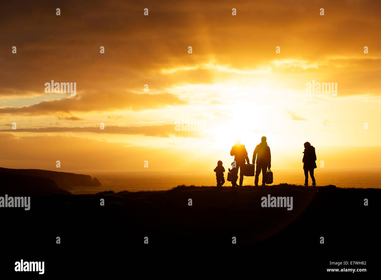 A silhouette of family and friends on a cliff top overlooking the coastline at sunset, Snug Cove, Kangaroo Island Stock Photo