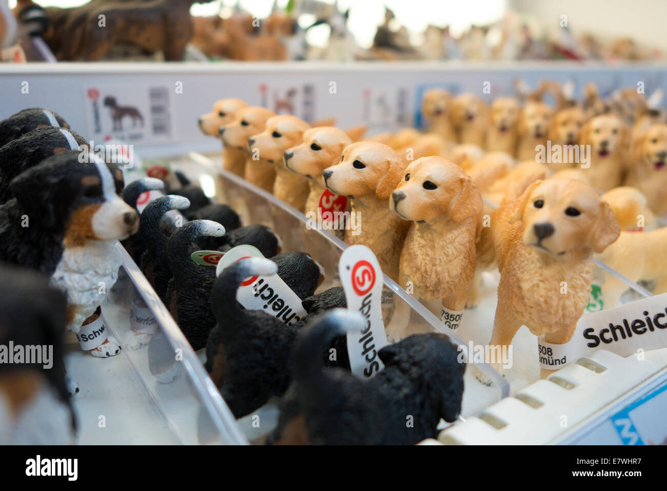 Rows of toy dog figurines are lined up on a shelf in a toy store. Golden retrievers and other breeds. Stock Photo