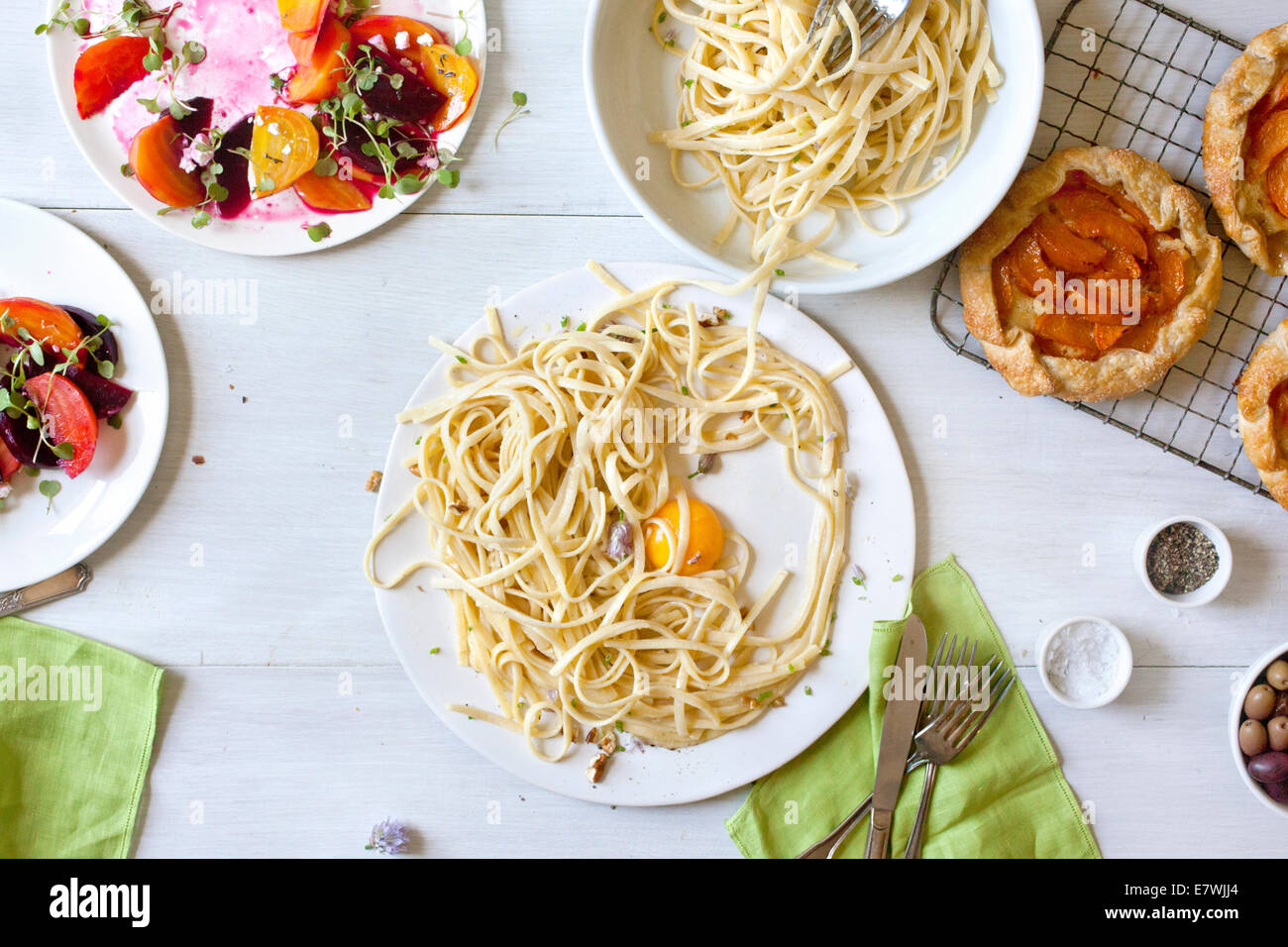 Messy spaghetti, beet salad, and apricot tart leftovers Stock Photo