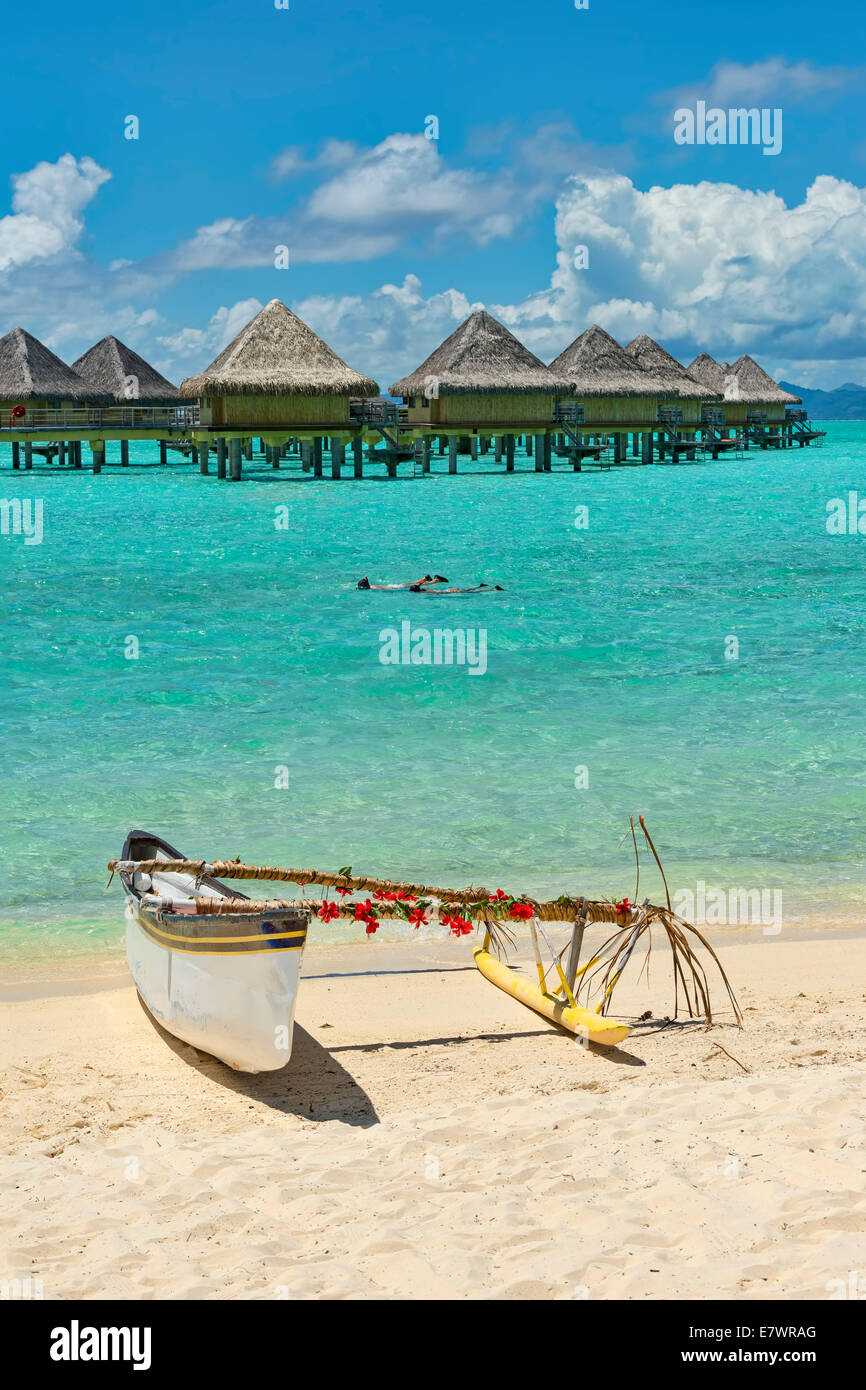 Decorated outrigger boat in front of overwater bungalows, Bora Bora, French Polynesia Stock Photo