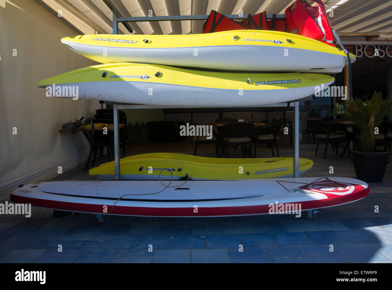 Paddle boards. Yellow and a red paddle board stacked, waiting to be
