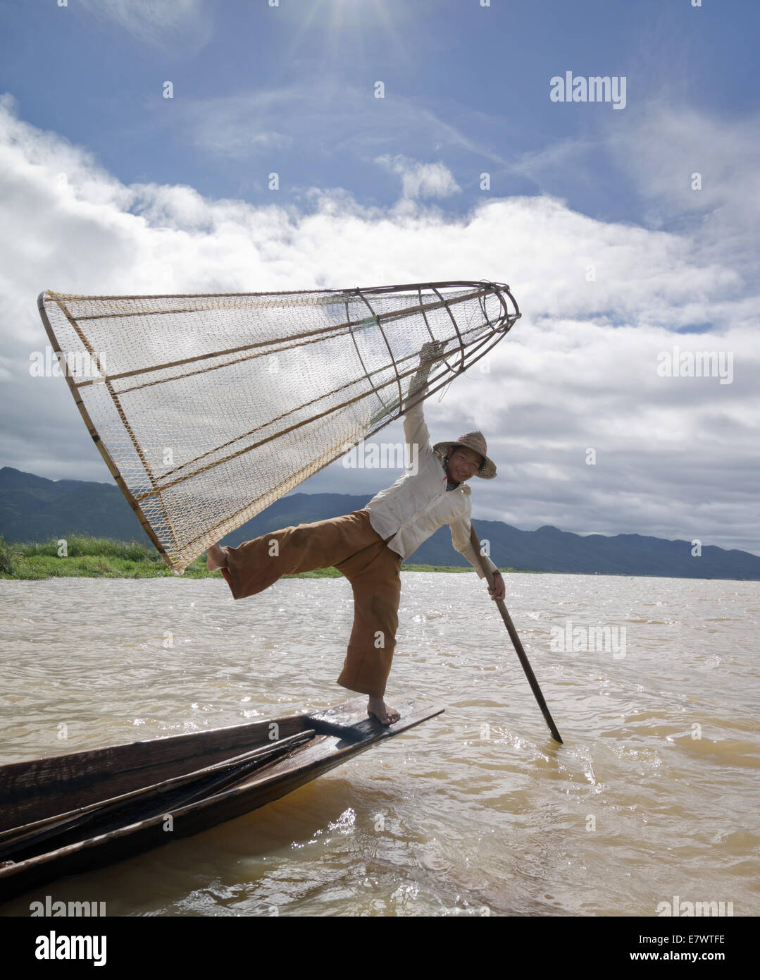 Burmese traditional fisherman holding conical trap ready to drop entrapping fish. Stock Photo