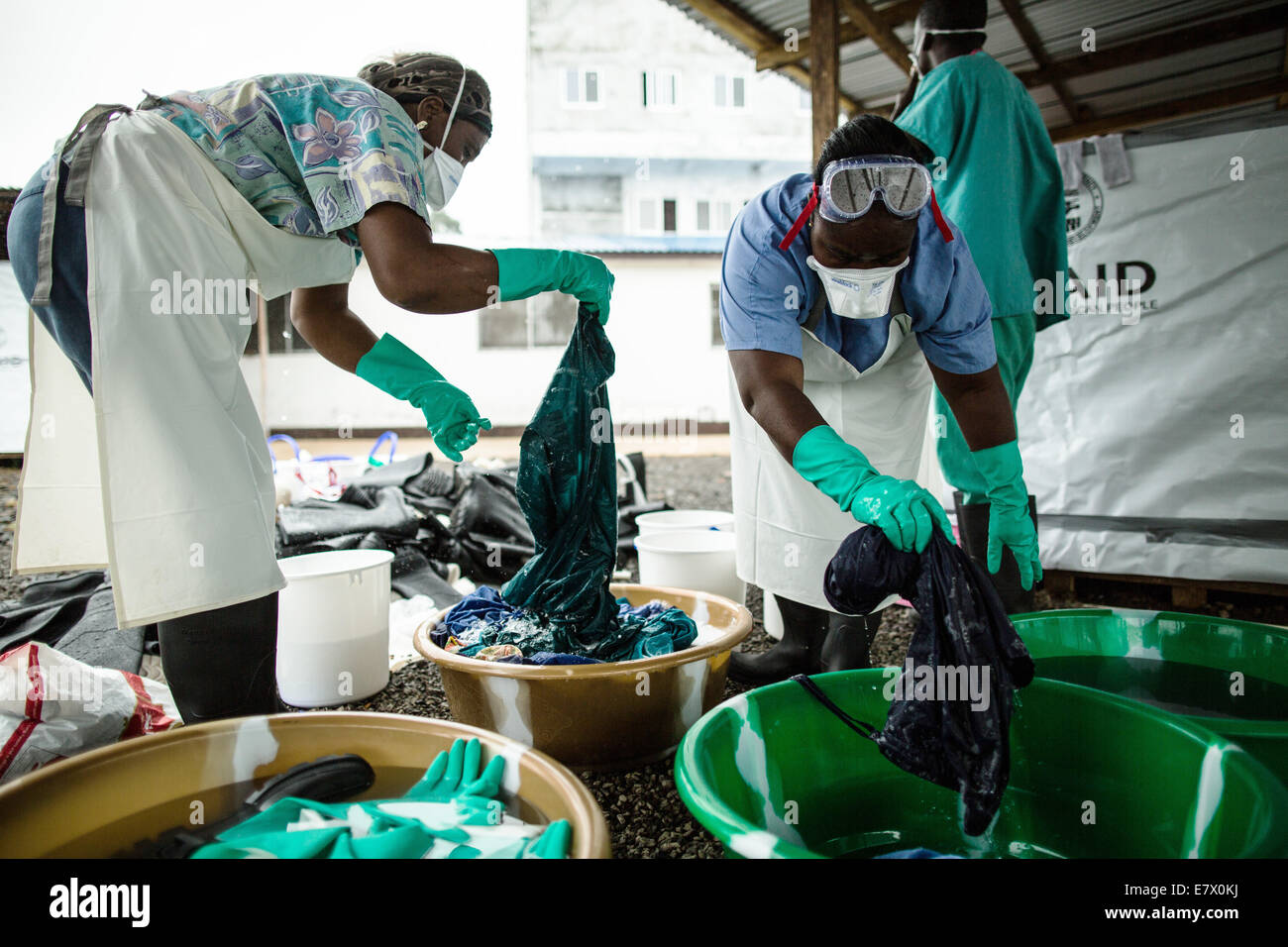 Health workers clean hospital scrubs and protective gear at the newly opened Island Clinic for Ebola treatment September 22, 2014 in Monrovia, Liberia. The facility opened by the WHO and the Ministry of Health in response to the surge of patients needing an Ebola Treatment. Stock Photo