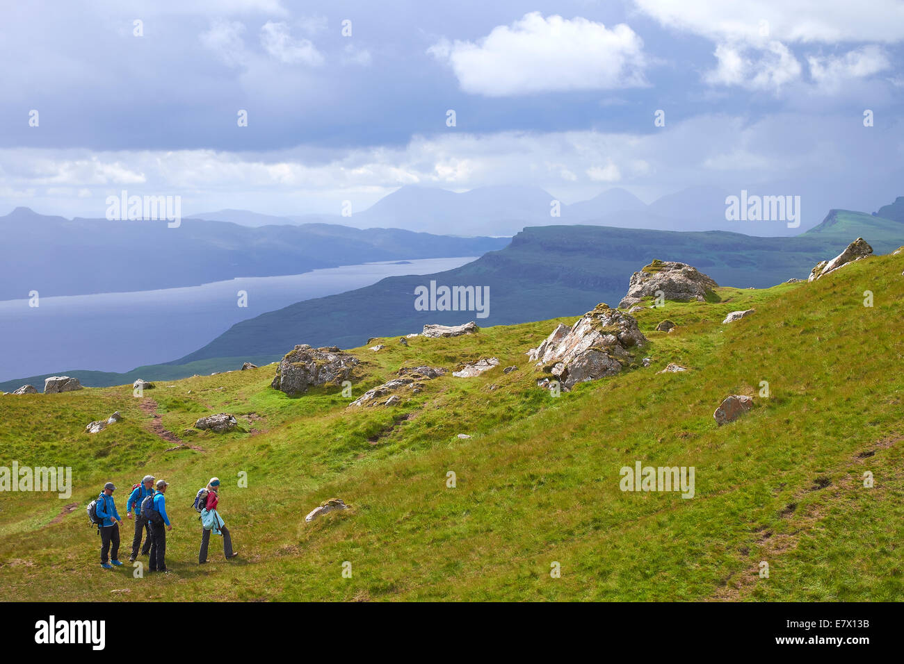 Hikers walking at Storr with the Quiraing And Loch Leathan in the distance, Isle of Skye, Scotland. Stock Photo