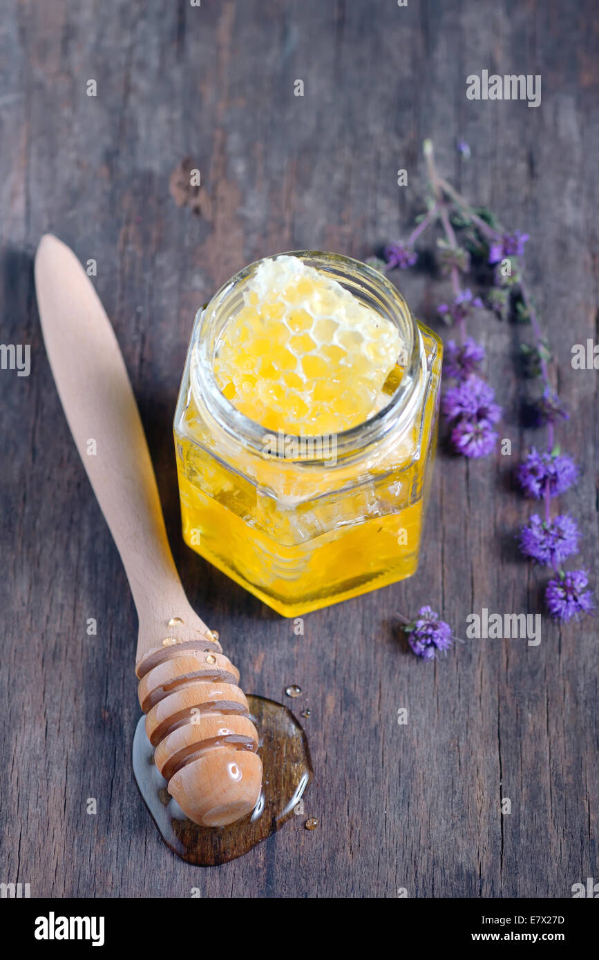 honeycomb and honey in glass jar and wild mint on old wooden background Stock Photo